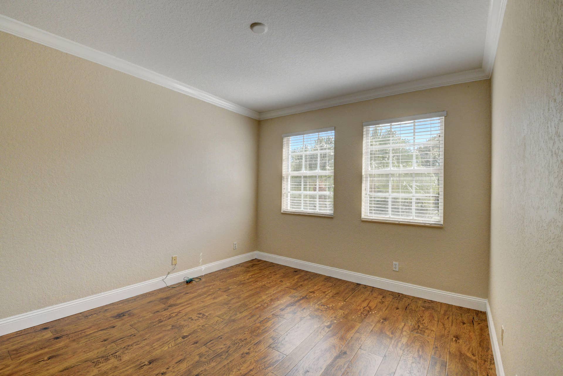 4353 Legacy Court, Delray Beach, FL 33445 Bedroom with two windows, wood-look flooring and crown molding.