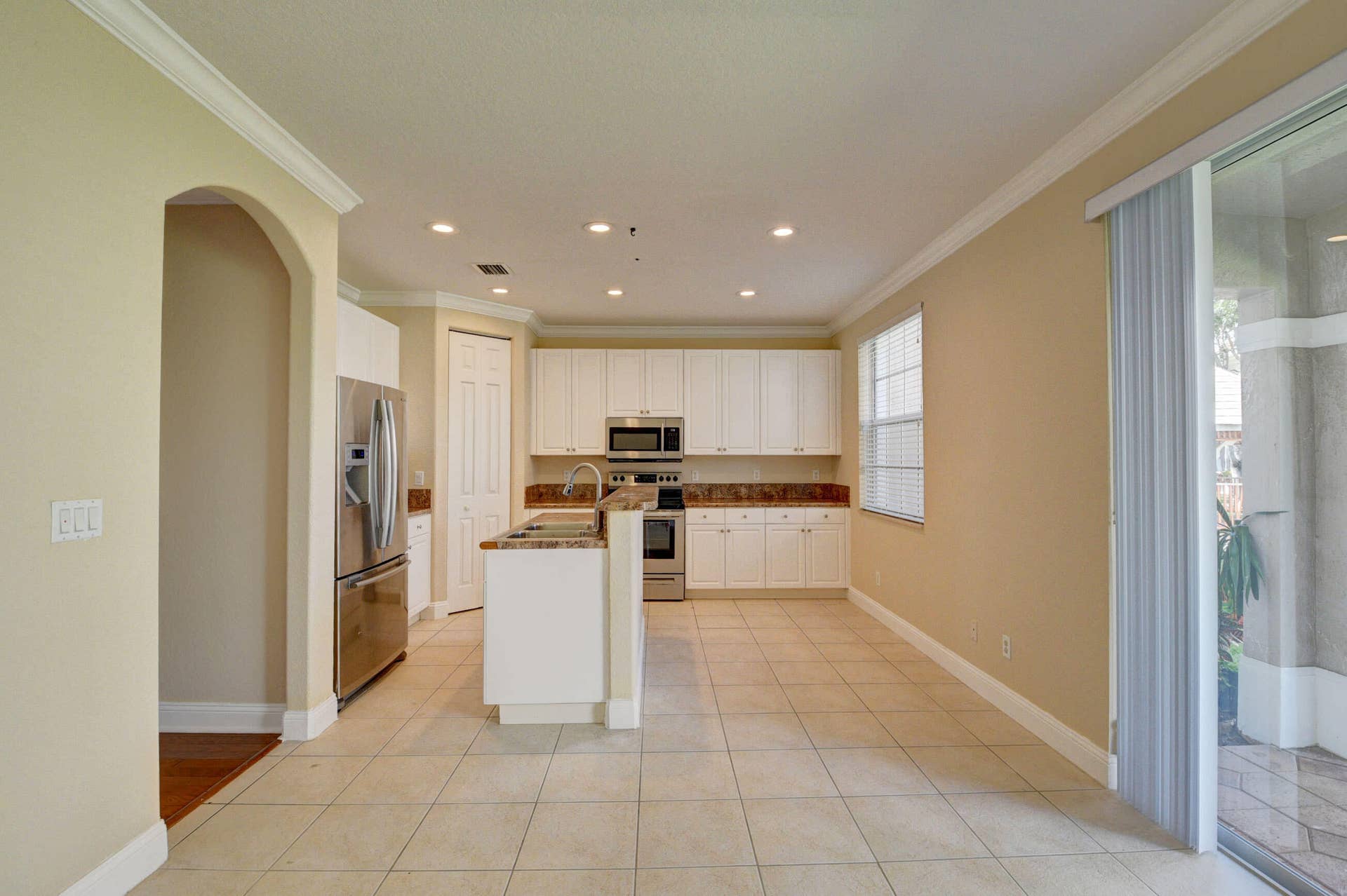 4353 Legacy Court, Delray Beach, FL 33445 Open kitchen and dining area with tile flooring and an arched doorway.