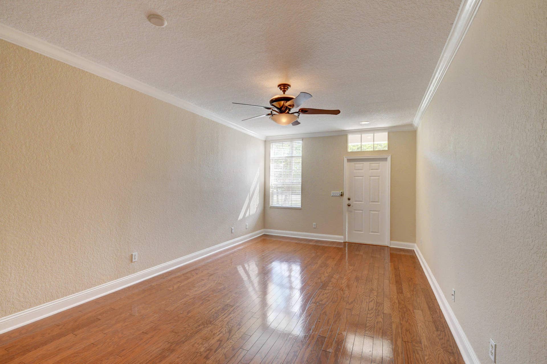4353 Legacy Court, Delray Beach, FL 33445 Living room with wood-look flooring, crown molding, ceiling fan and front entry.