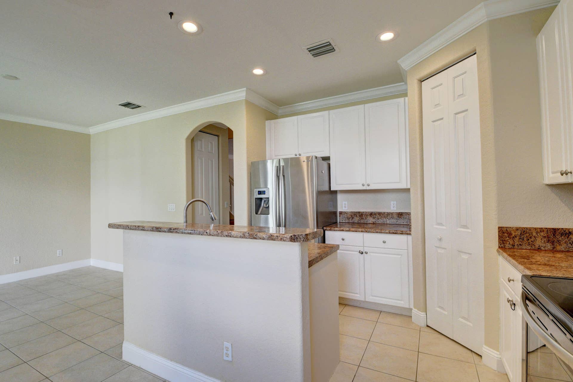 4353 Legacy Court, Delray Beach, FL 33445 Kitchen island and stainless steel refrigerator with white cabinetry.