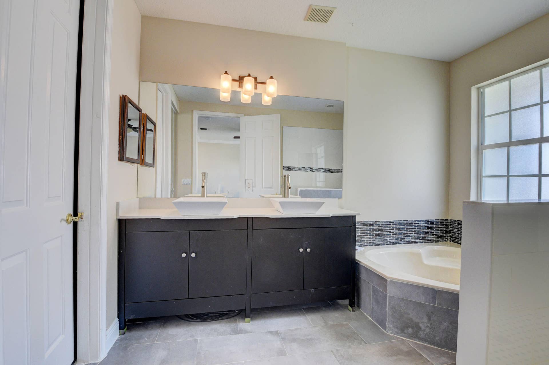 4353 Legacy Court, Delray Beach, FL 33445 Bathroom with dual-sink dark vanity, window and soaking tub.