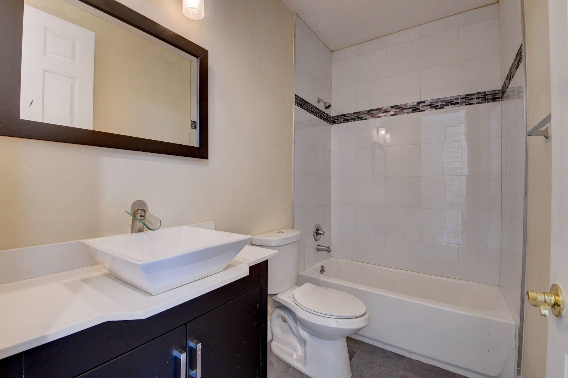 4353 Legacy Court, Delray Beach, FL 33445 Bathroom with vessel sink, dark vanity, framed mirror and tub/shower with accent tile.