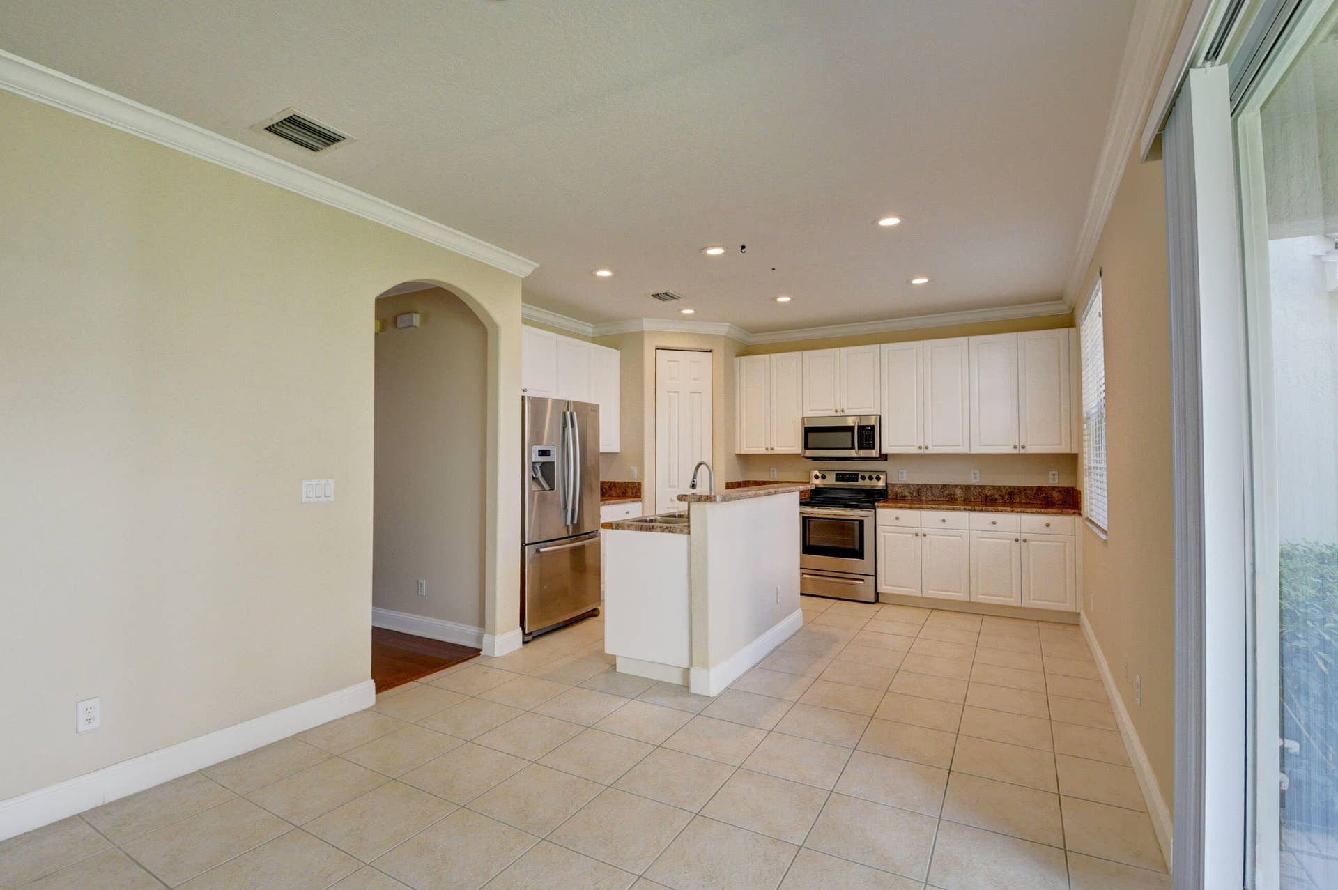 4353 Legacy Court, Delray Beach, FL 33445 Kitchen and dining area with tile flooring, crown molding and an arched entry.