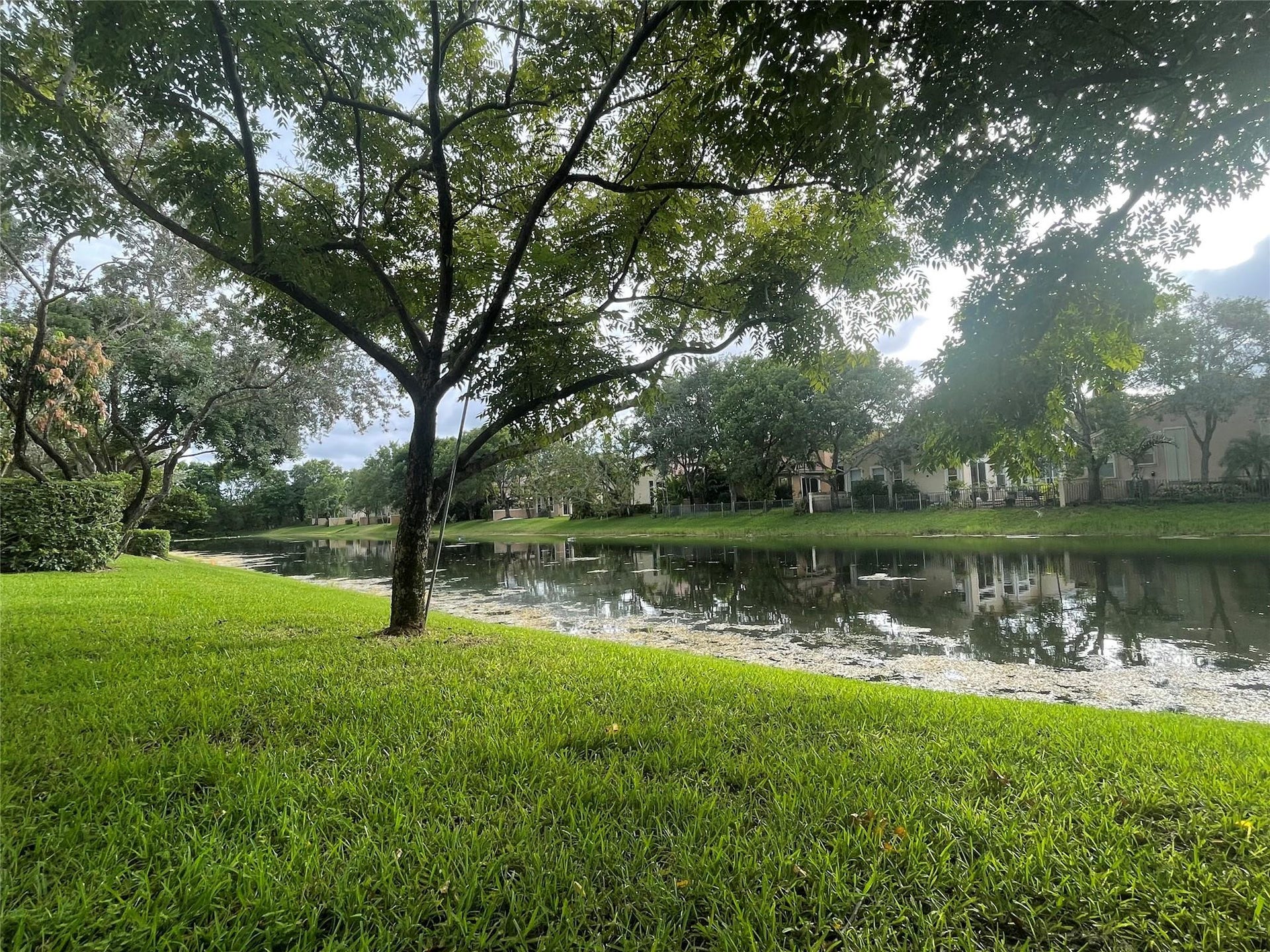 5780 NW 120TH Avenue, Coral Springs, Coral Springs, FL 33076 Waterfront property featuring a manicured lawn, mature trees, and natural landscaping