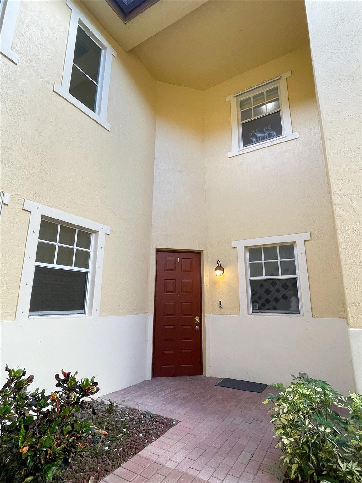 5780 NW 120TH Avenue, Coral Springs, Coral Springs, FL 33076 Entryway featuring a double-height ceiling, stucco exterior, paved walkway, and multiple multi-pane windows
