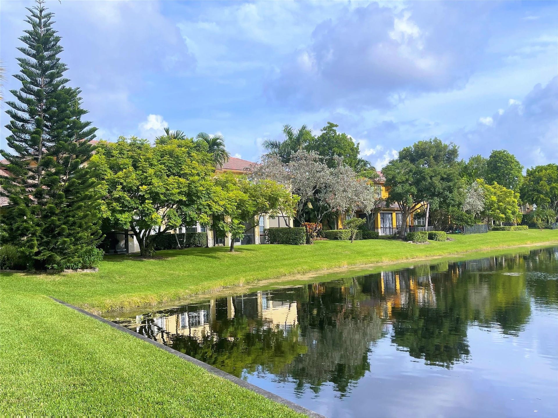 5780 NW 120TH Avenue, Coral Springs, Coral Springs, FL 33076 Waterfront property featuring manicured lawns, mature specimen trees, and established landscaping
