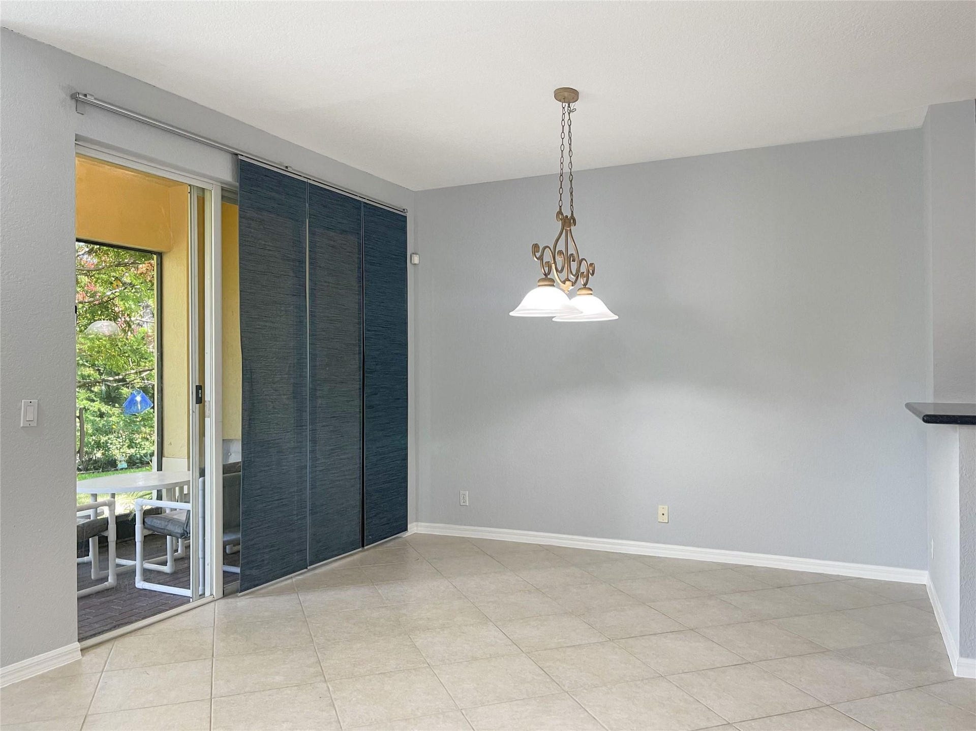 5780 NW 120TH Avenue, Coral Springs, Coral Springs, FL 33076 Ceramic tile flooring, sliding glass door with integrated panel blinds, and a decorative multi-light chandelier