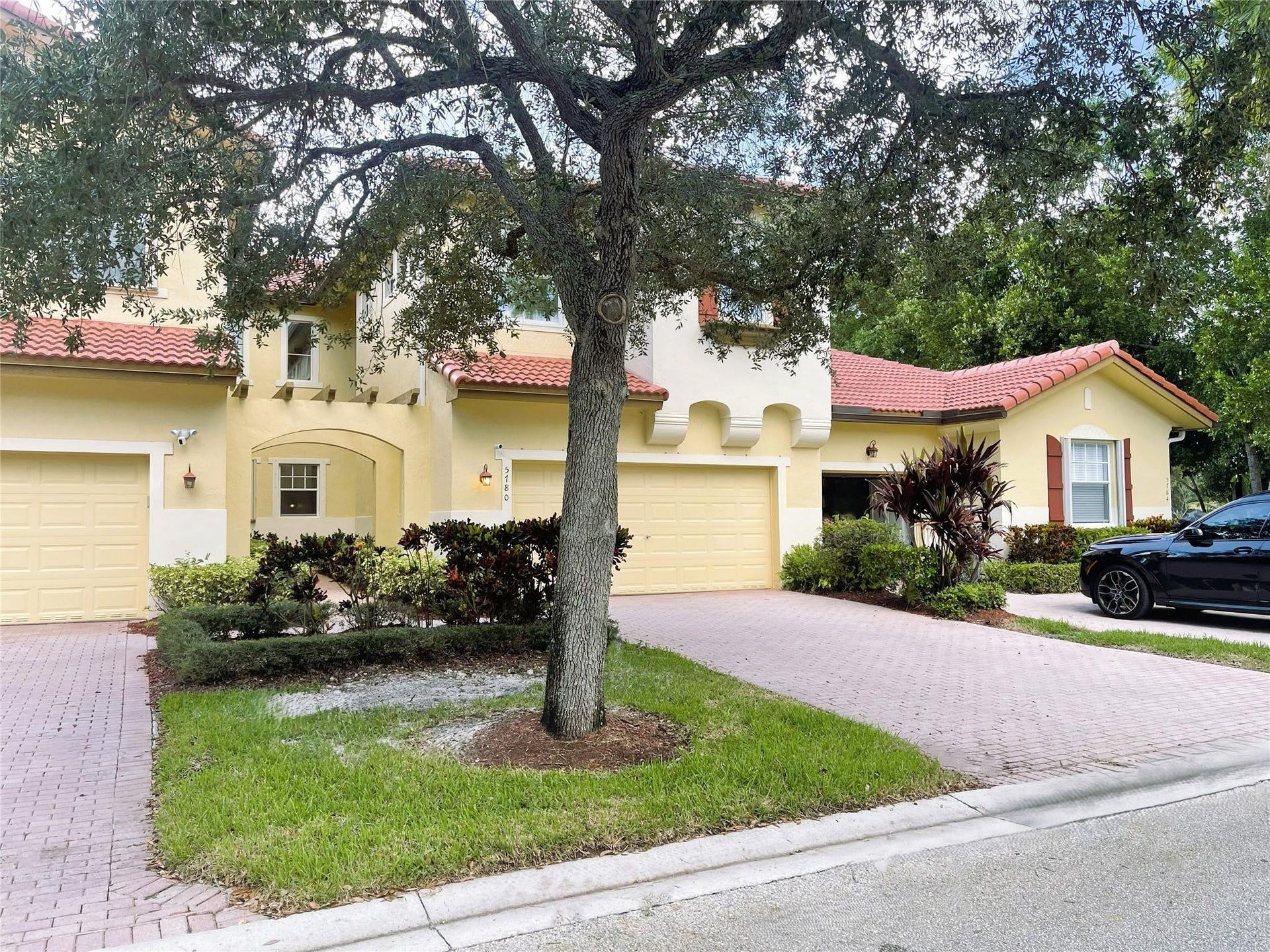 5780 NW 120TH Avenue, Coral Springs, Coral Springs, FL 33076 Mediterranean-style exterior featuring a clay tile roof, arched entryway, stucco facade, and an expansive brick-paver driveway