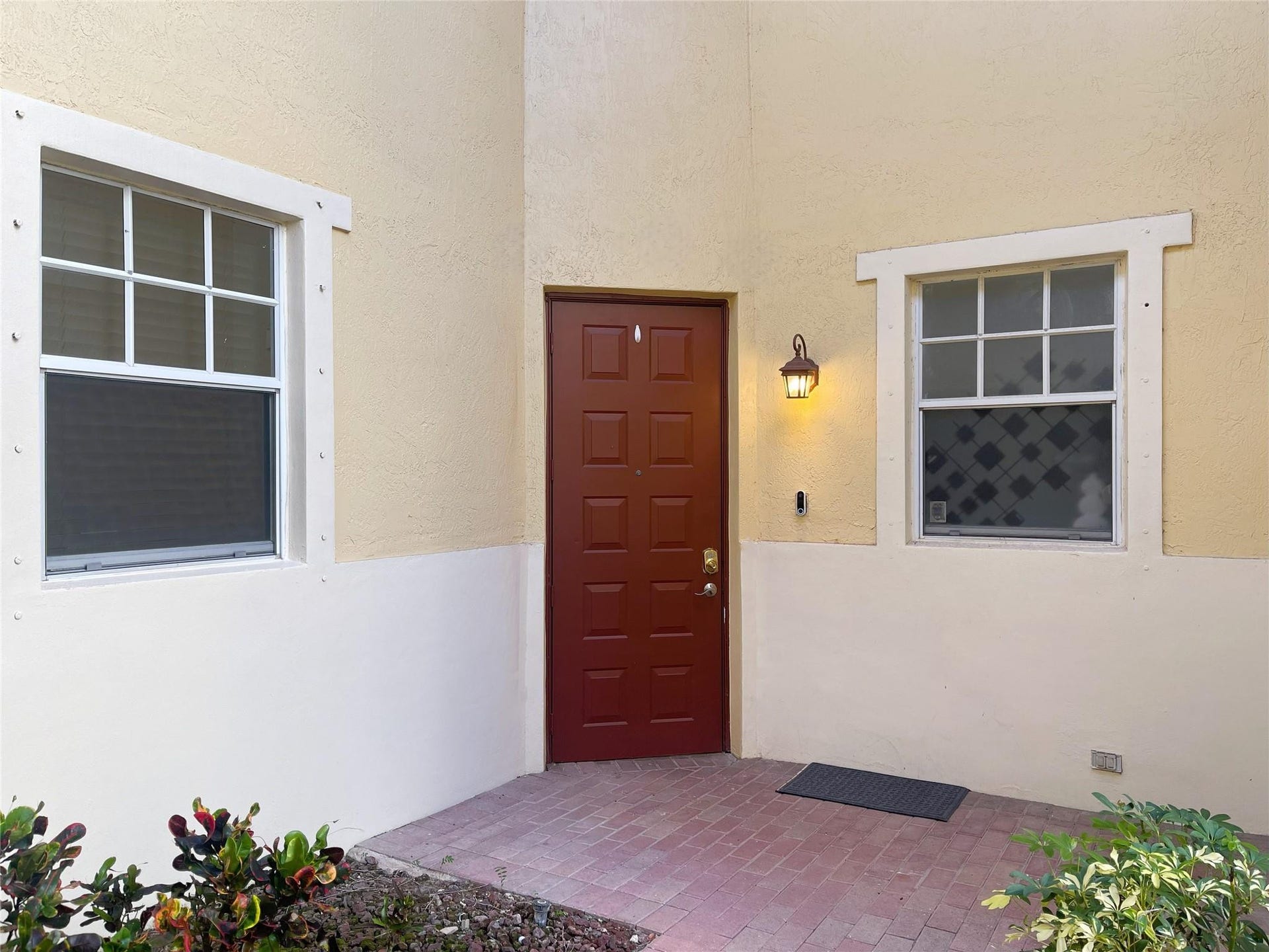 5780 NW 120TH Avenue, Coral Springs, Coral Springs, FL 33076 Stucco exterior featuring a dual-tone facade, recessed paneled entry door, brick-paver porch, and multi-pane windows with decorative trim