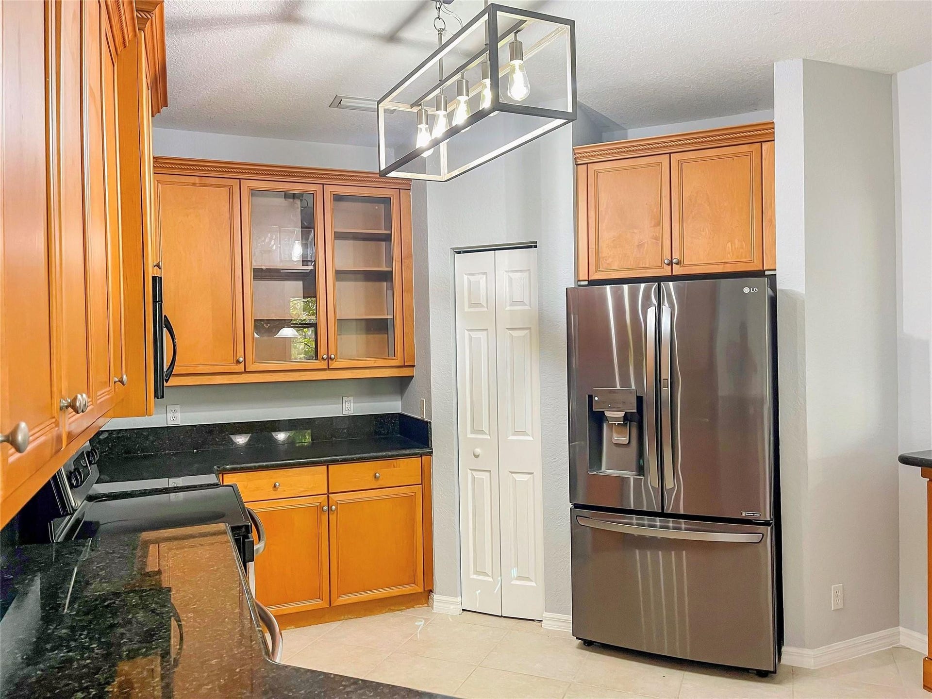 5780 NW 120TH Avenue, Coral Springs, Coral Springs, FL 33076 Kitchen featuring wood cabinetry, stone countertops, stainless steel French door refrigerator, glass-front upper cabinet doors, and a rectangular metal pendant light fixture