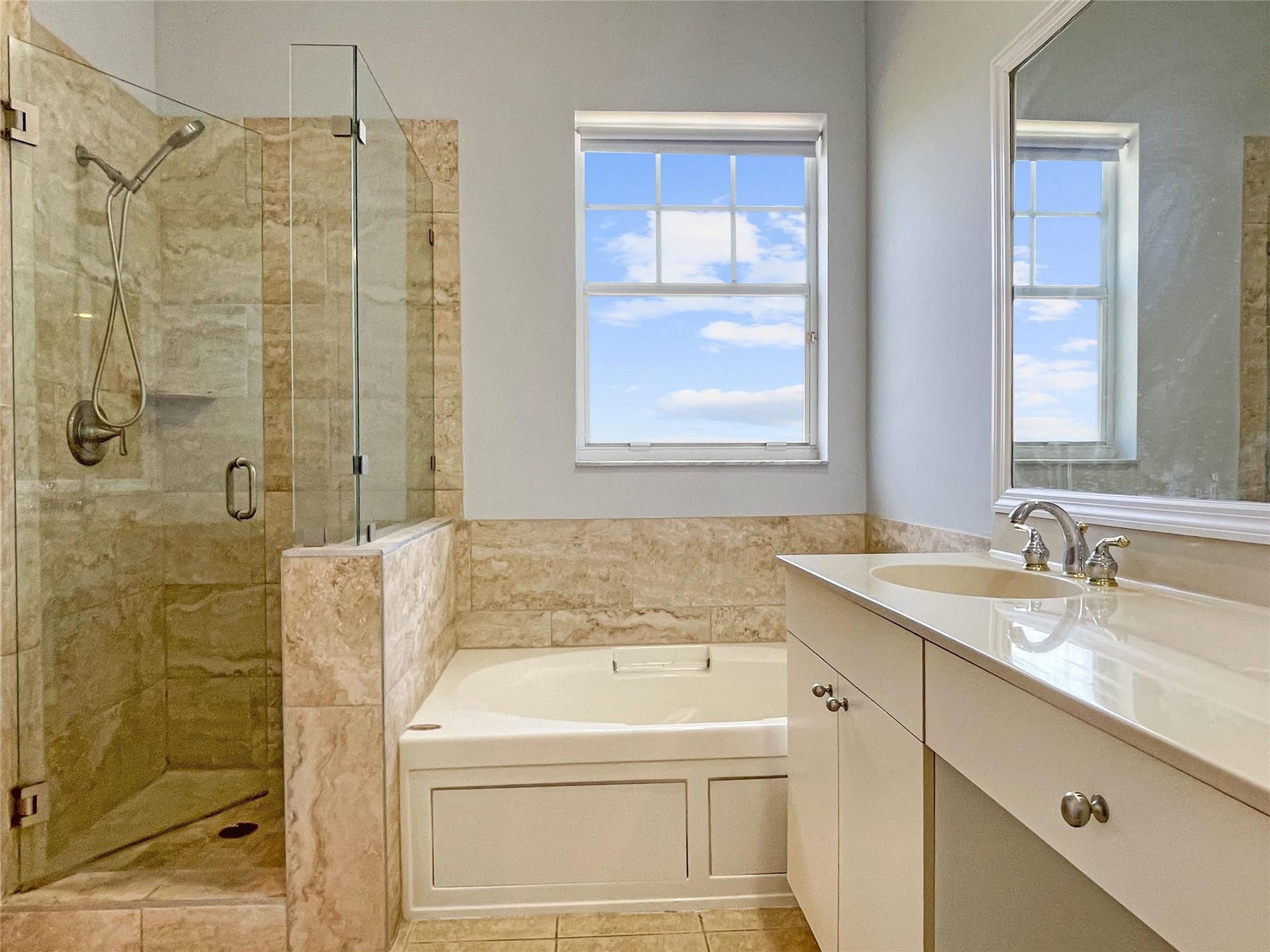 5780 NW 120TH Avenue, Coral Springs, Coral Springs, FL 33076 Bathroom featuring a glass-enclosed walk-in shower with stone tile surround, a built-in soaking tub, a single-sink vanity with countertop, and a framed mirror