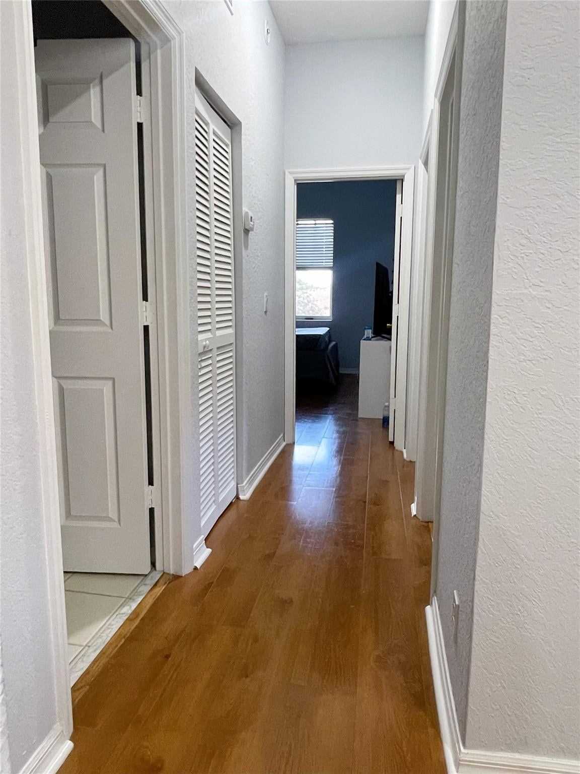 5780 NW 120TH Avenue, Coral Springs, Coral Springs, FL 33076 Hallway featuring wood-finish flooring, white paneled doors, and louvered closet doors