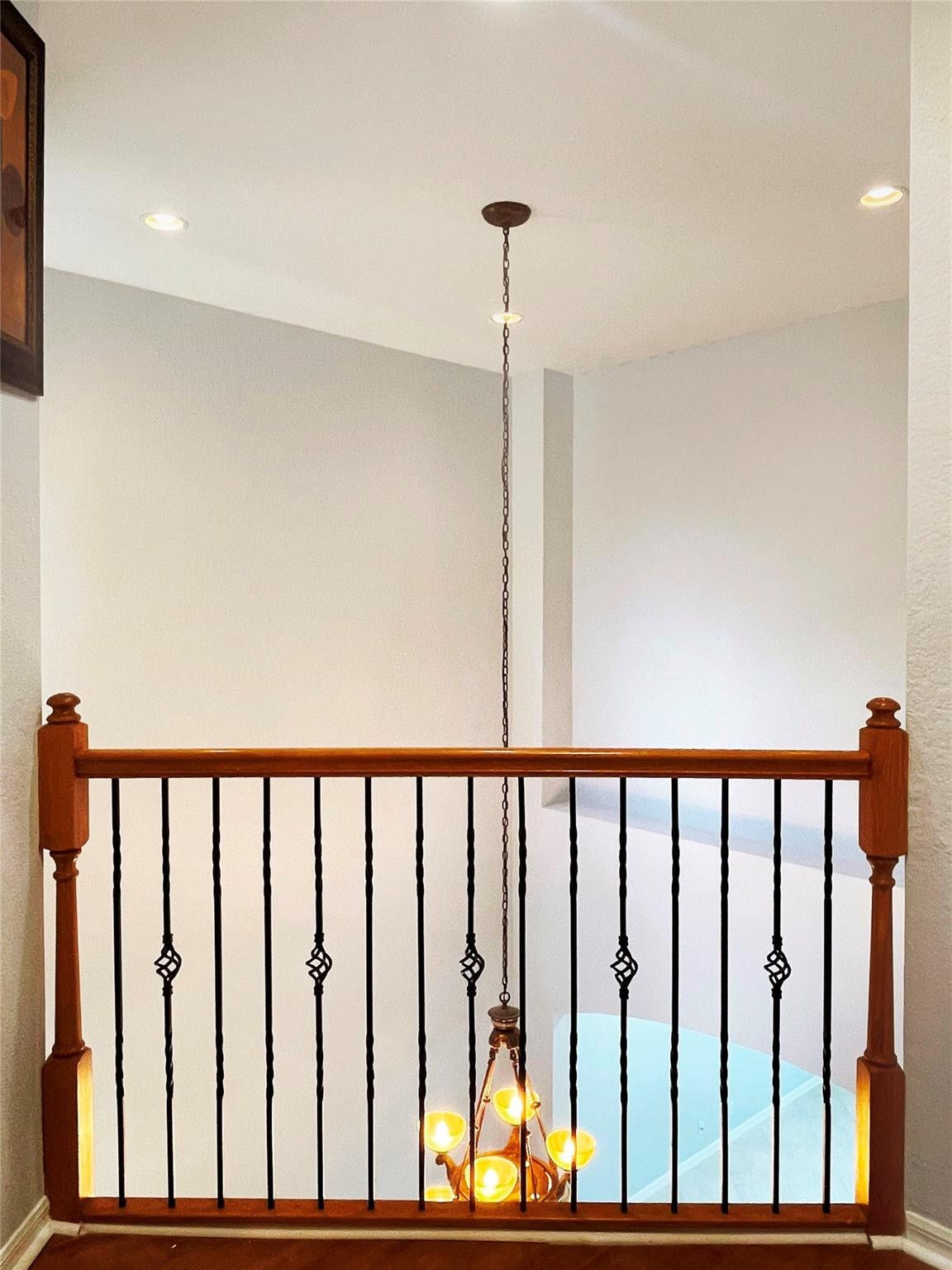 5780 NW 120TH Avenue, Coral Springs, Coral Springs, FL 33076 Interior railing featuring wood handrails, wood newel posts, and decorative metal balusters, accented by a multi-light pendant fixture with a chain suspension
