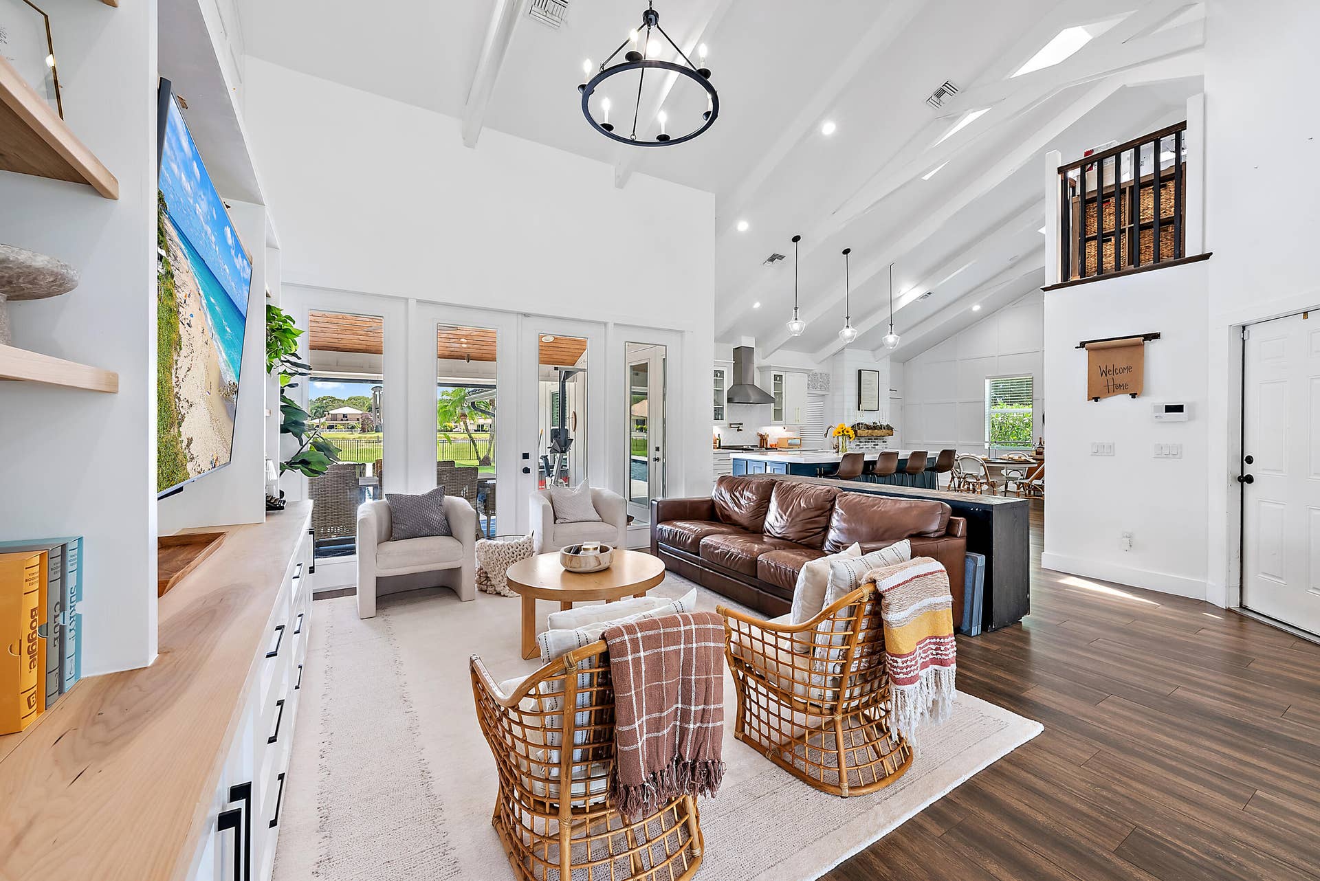 6204 SAND PINE Court, Jupiter, Jupiter, FL 33458 Vaulted white ceilings with exposed beams, wood-look tile flooring, built-in media console with shelving, white French doors, and an upper-level interior balcony with dark wood railing