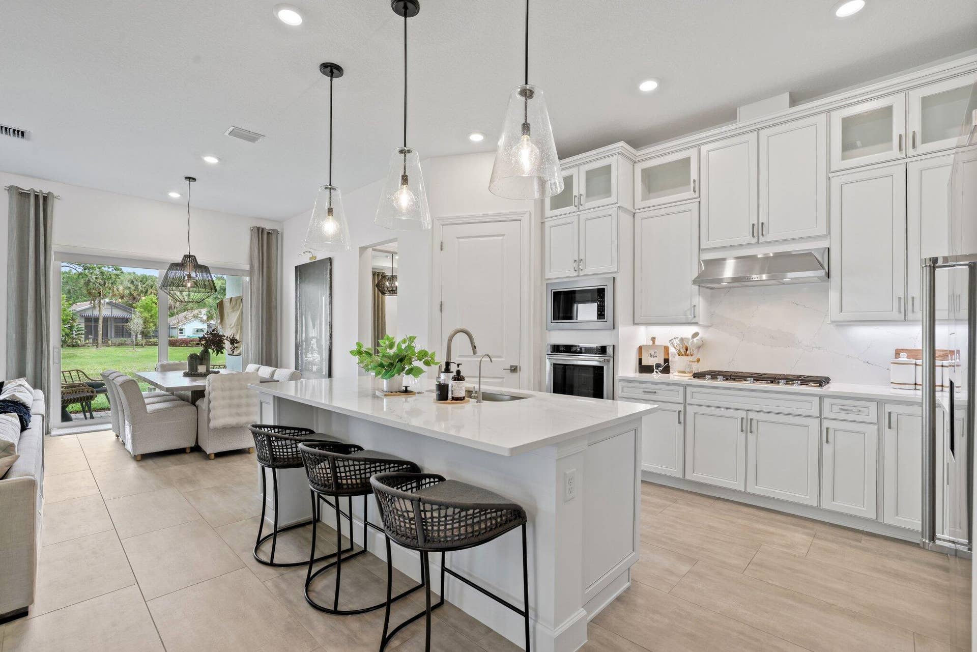 205 GEILLIS Path, Delray Beach, FL 33445 Kitchen featuring white shaker-style cabinetry, a large central island with quartz countertops, stainless steel built-in double wall ovens, a gas cooktop with a stainless steel range hood, and porcelain tile flooring