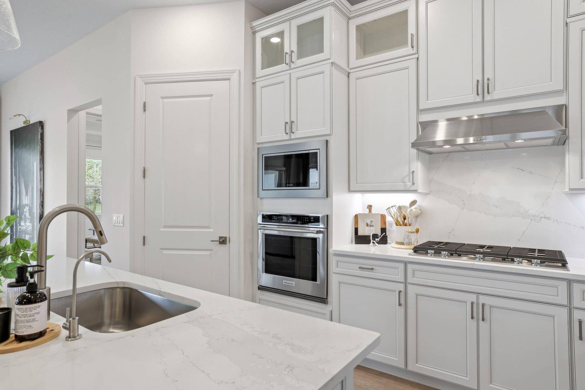205 GEILLIS Path, Delray Beach, FL 33445 Kitchen featuring white cabinetry, quartz countertops with a full-height stone backsplash, stainless steel built-in double ovens, a gas cooktop, and a stainless steel kitchen faucet