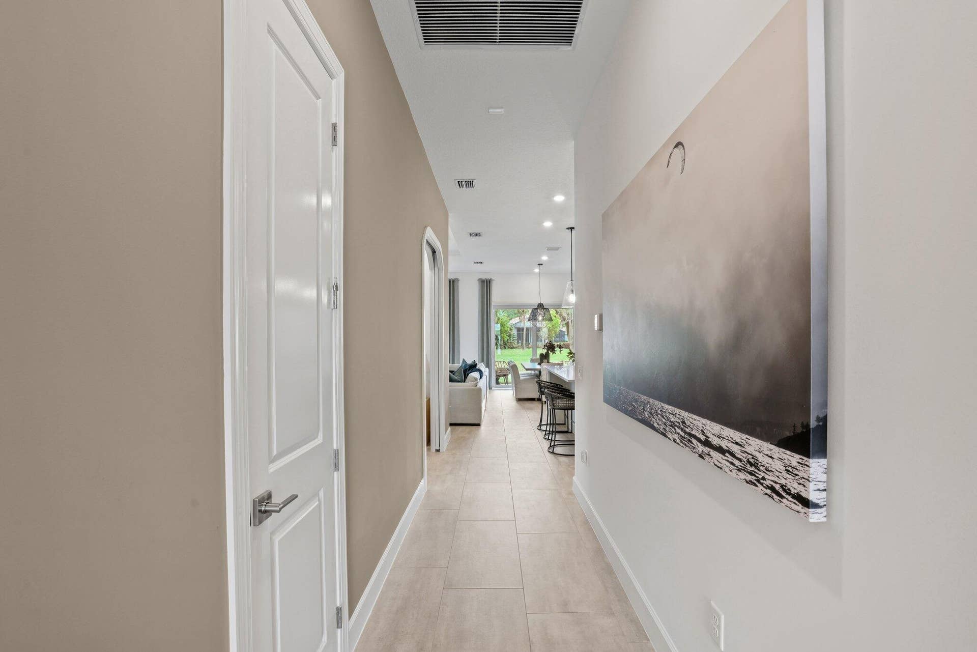 205 GEILLIS Path, Delray Beach, FL 33445 Interior hallway featuring large-format ceramic tile flooring, neutral wall paint, a multi-panel door with metallic hardware, and recessed lighting
