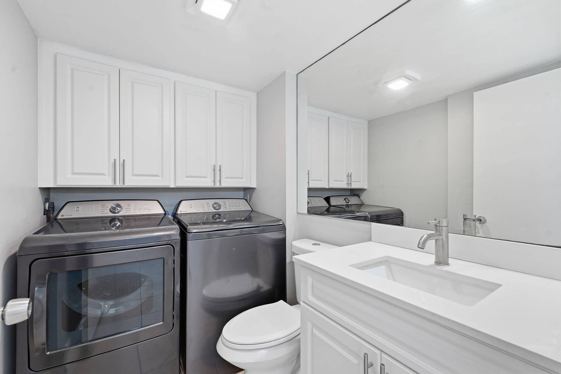 236 CHARTER Way, West Palm Beach, FL 33407 White paneled cabinetry, integrated sink, and expansive vanity mirror