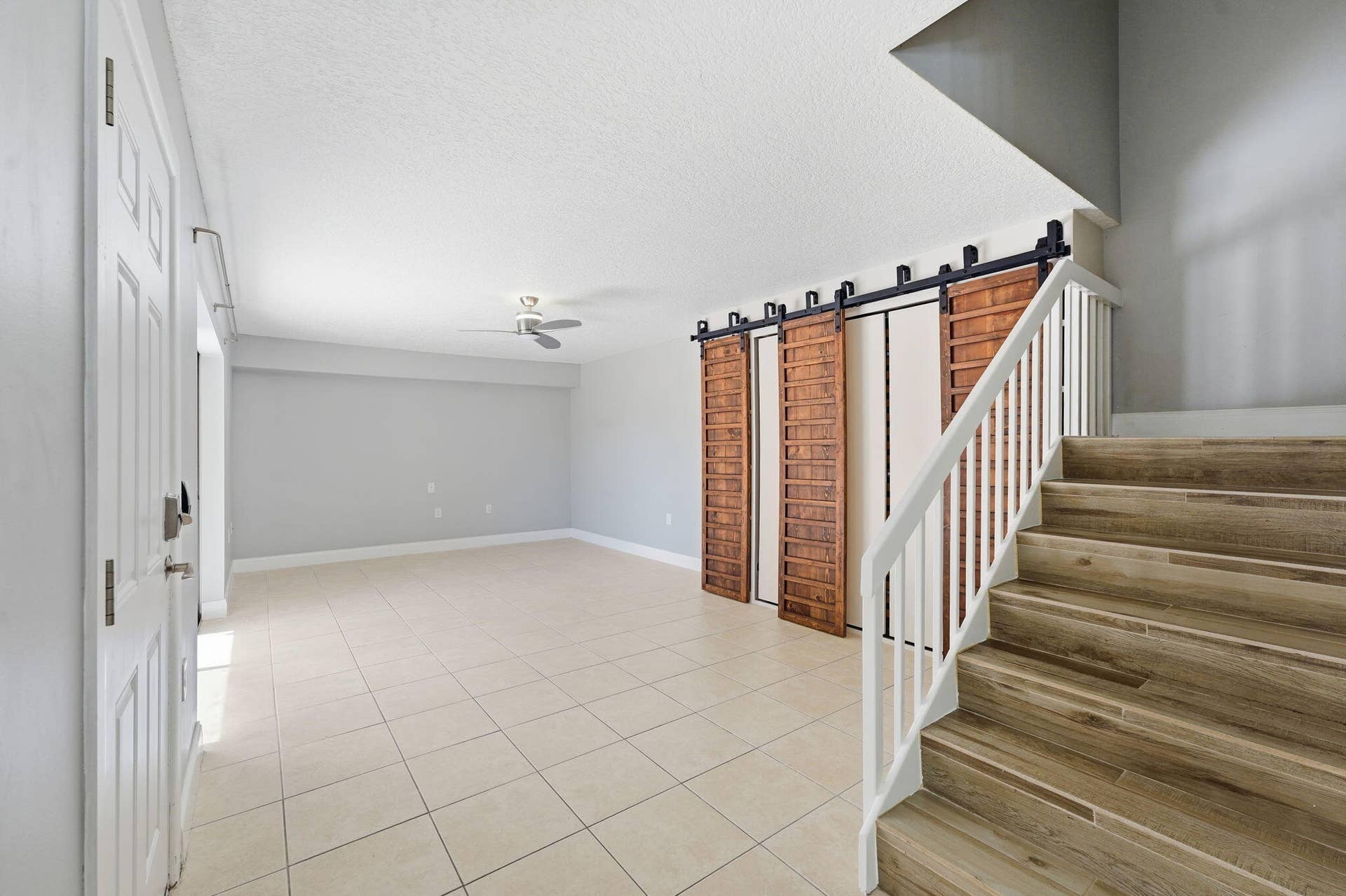 236 CHARTER Way, West Palm Beach, FL 33407 Wood-finish staircase with white railings, tile flooring, and wood-paneled barn doors with black hardware