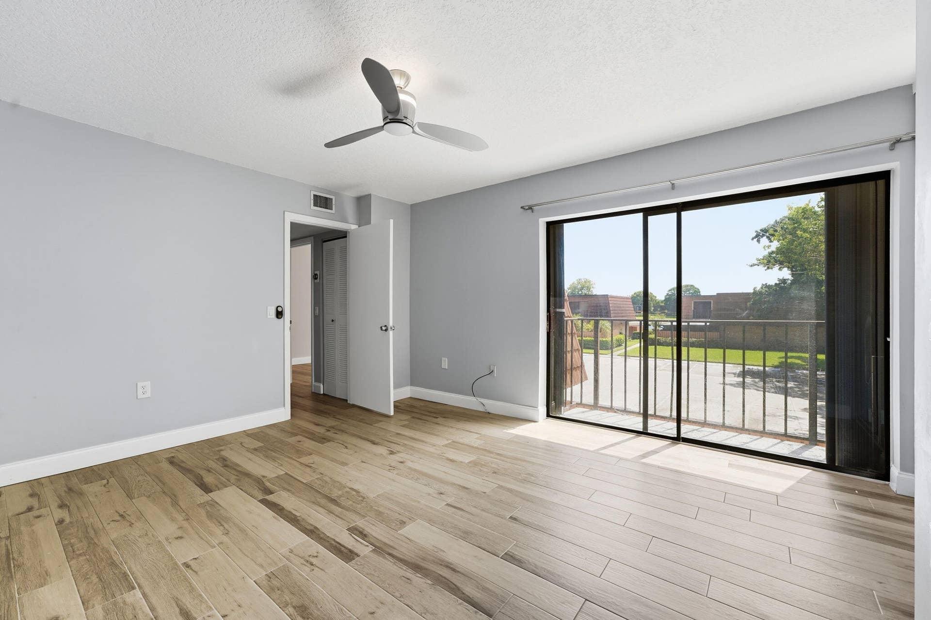 236 CHARTER Way, West Palm Beach, FL 33407 Wood-finish plank flooring, ceiling fan, and sliding glass door with balcony access