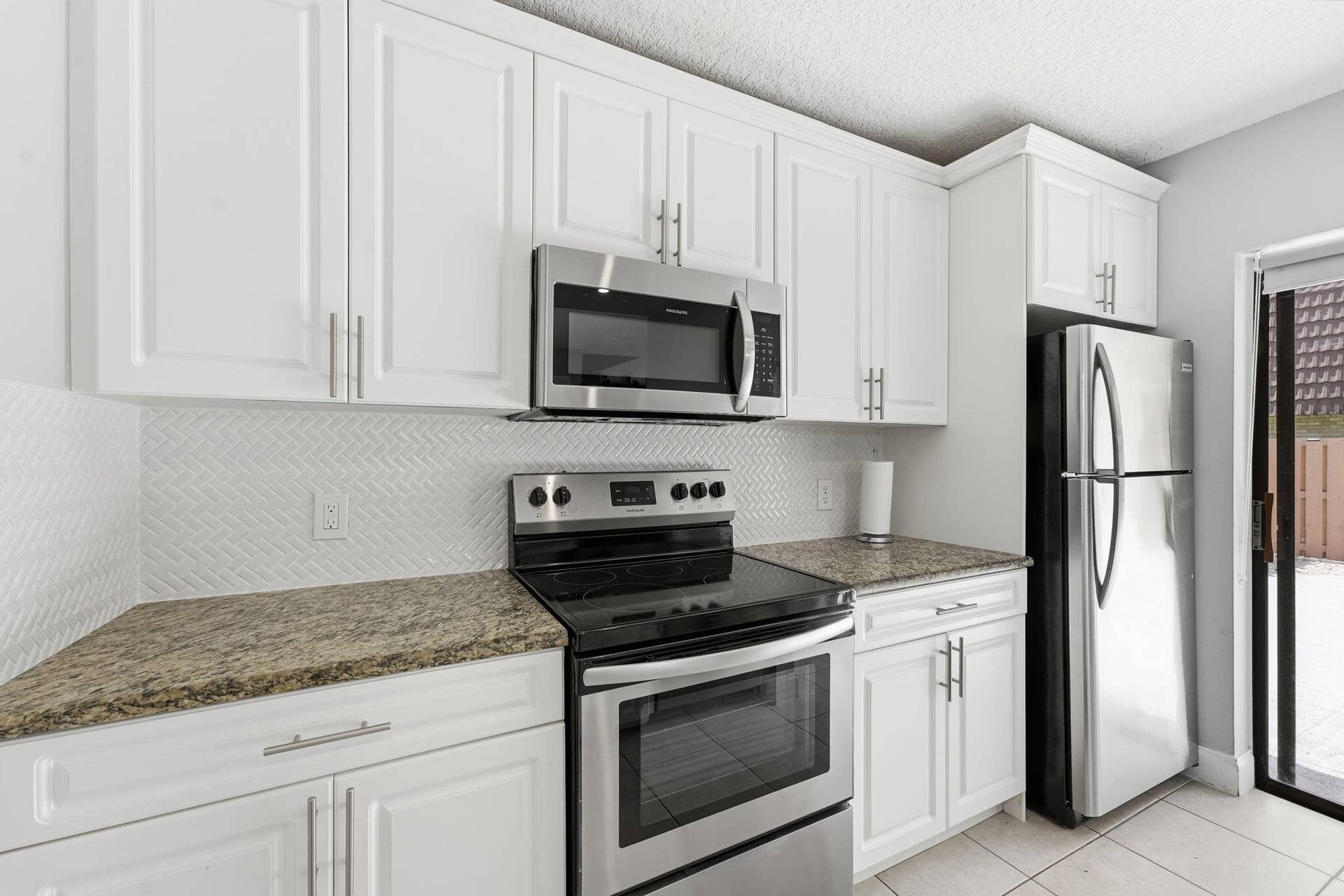 236 CHARTER Way, West Palm Beach, FL 33407 White cabinetry with stainless steel appliances, stone countertops, and a herringbone tile backsplash