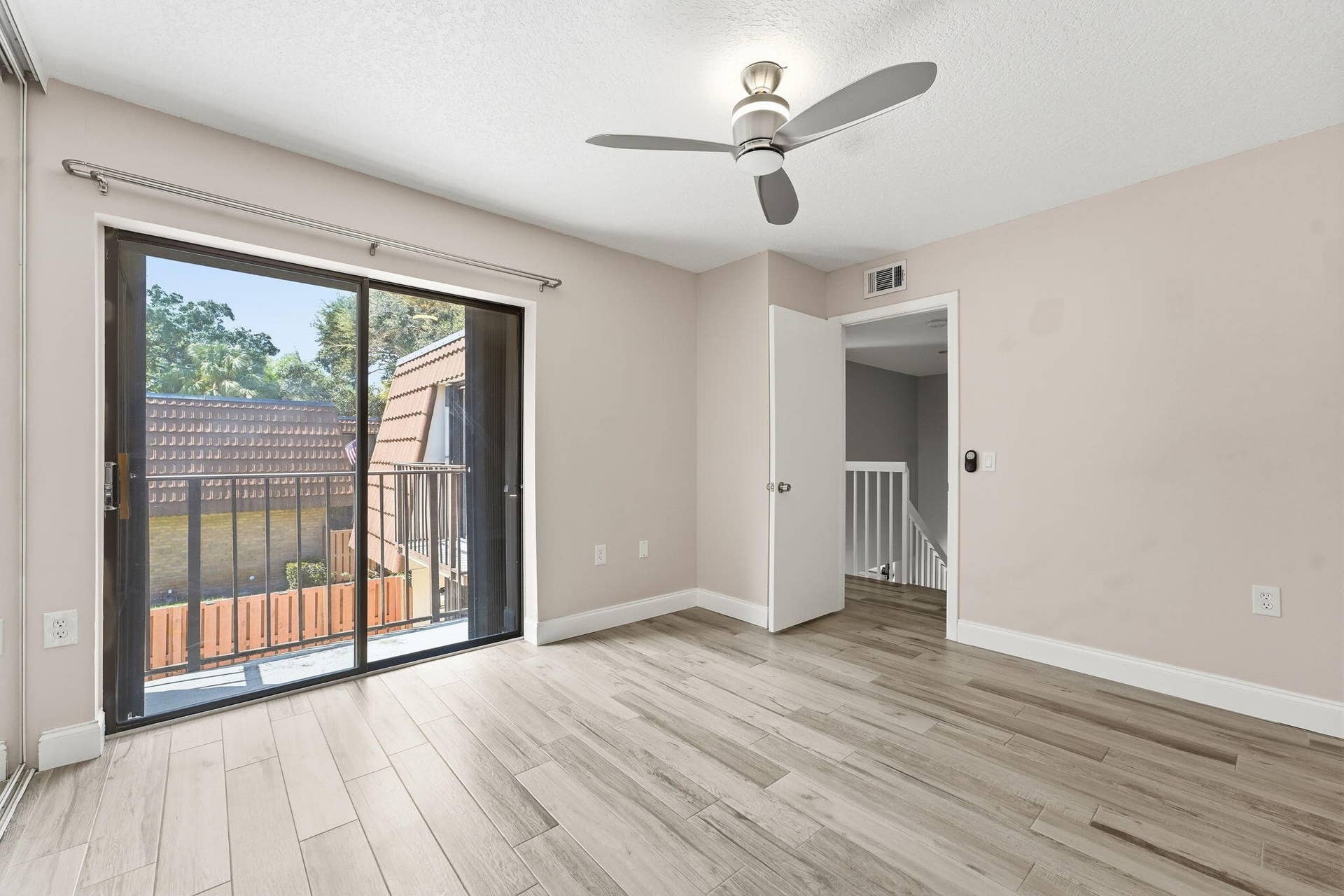 236 CHARTER Way, West Palm Beach, FL 33407 Sliding glass door to balcony, wood-finish flooring, ceiling fan, and white trim