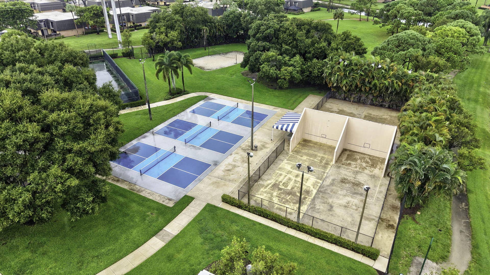 236 CHARTER Way, West Palm Beach, FL 33407 Multiple pickleball courts, two racquetball courts, a sand volleyball court, and lush landscaping