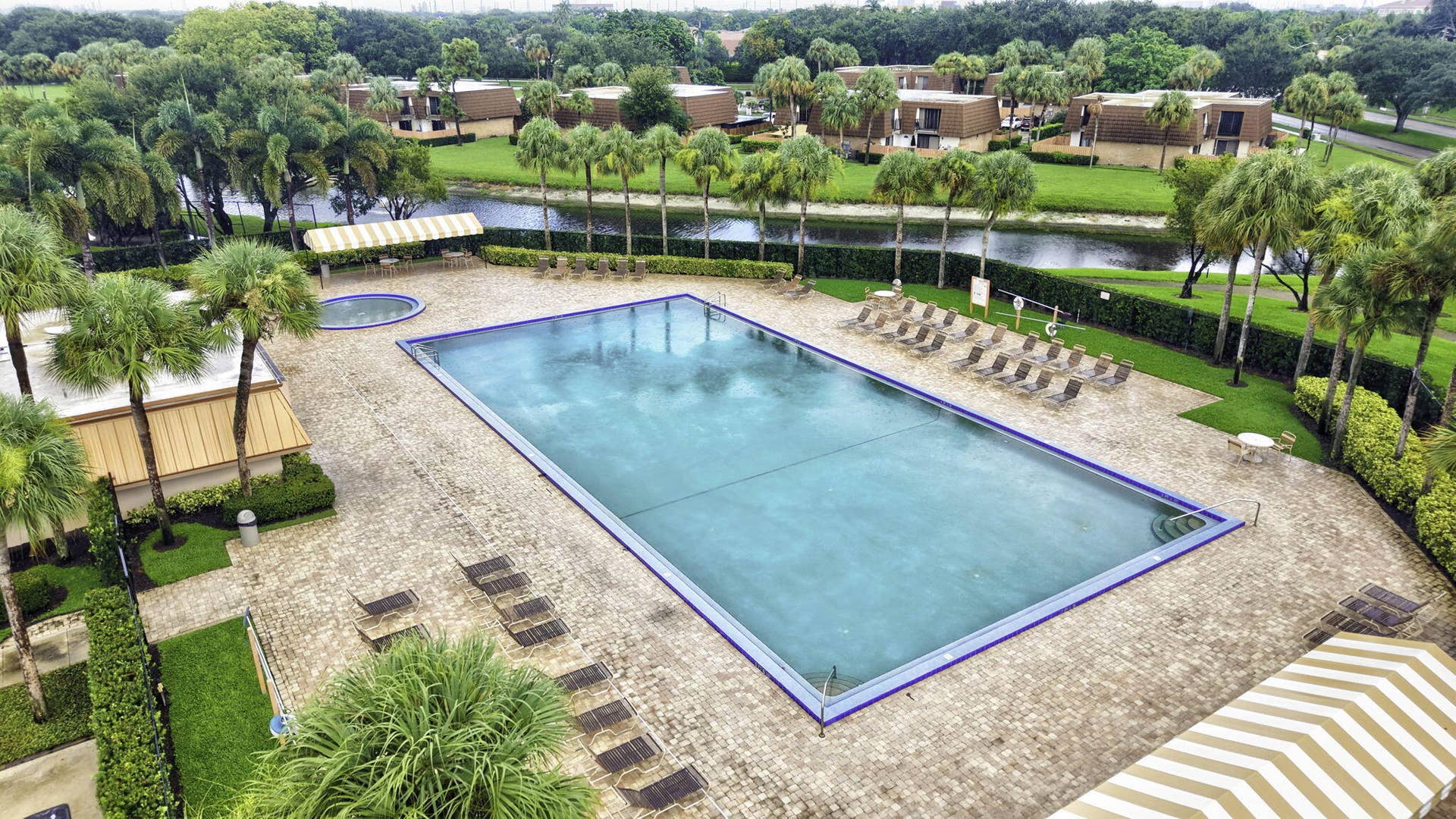 236 CHARTER Way, West Palm Beach, FL 33407 Expansive outdoor pool area featuring a rectangular swimming pool, a separate circular spa, and an extensive paver deck