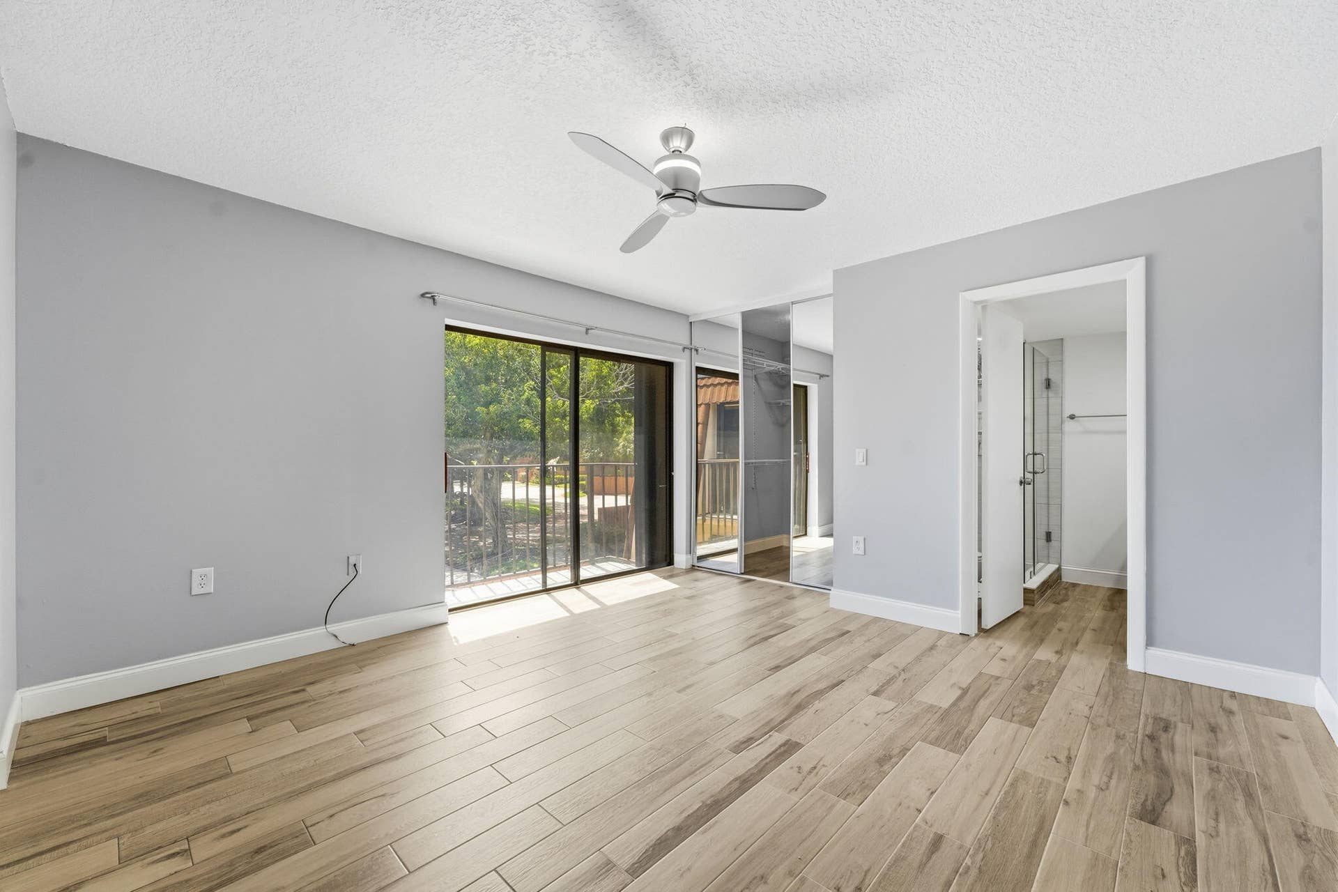 236 CHARTER Way, West Palm Beach, FL 33407 Wood-finish flooring, sliding glass doors to outdoor space, ceiling fan, mirrored closet doors, and an en-suite bathroom with a glass-enclosed shower