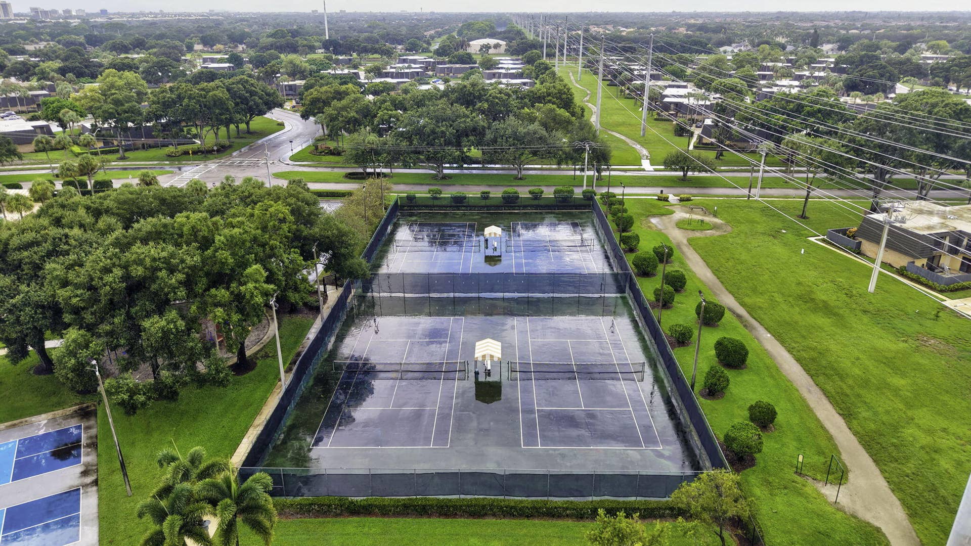 236 CHARTER Way, West Palm Beach, FL 33407 Two hard-surface tennis courts with perimeter fencing, surrounded by manicured lawns and mature trees