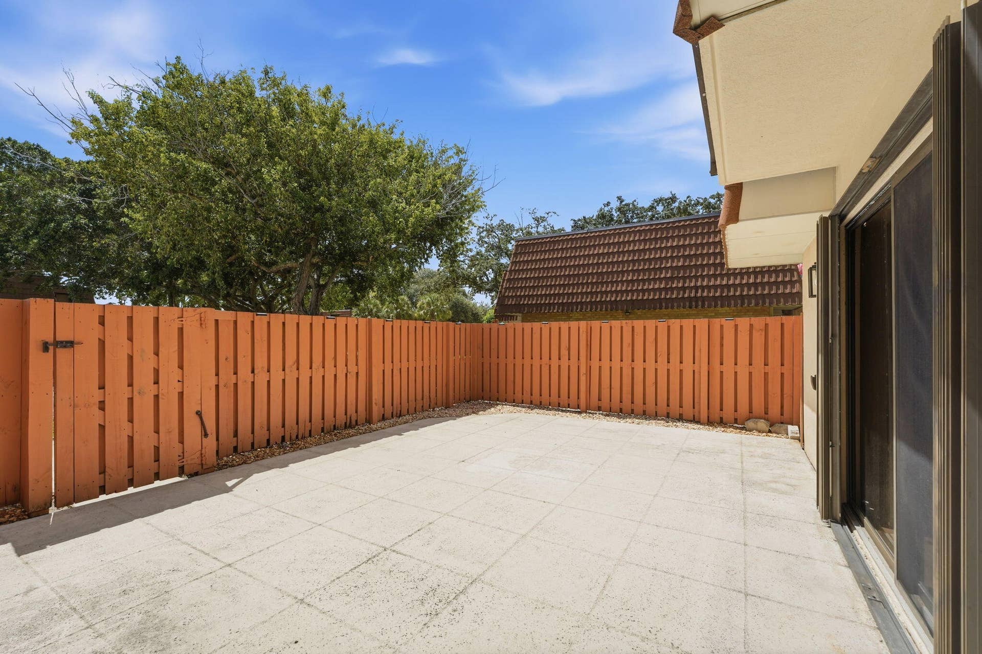 236 CHARTER Way, West Palm Beach, FL 33407 Paved outdoor patio space with wood fencing and a sliding glass door