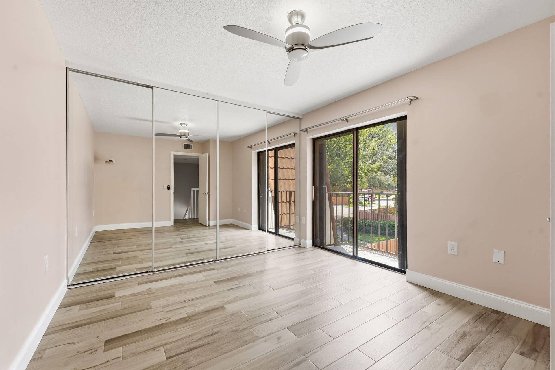 236 CHARTER Way, West Palm Beach, FL 33407 Wood-finish flooring, full-wall mirrored closet doors, ceiling fan with integrated lighting, and sliding glass doors opening to an outdoor balcony