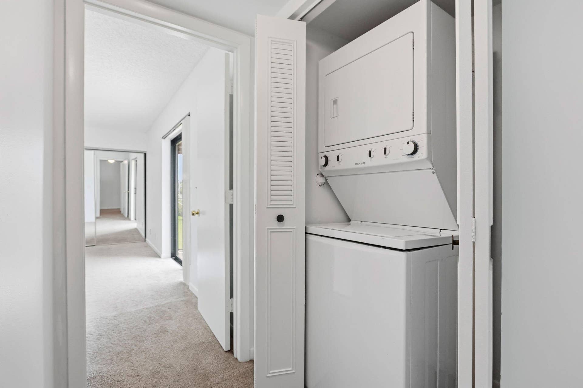 Stackable washer and dryer within a louvered bifold door enclosure