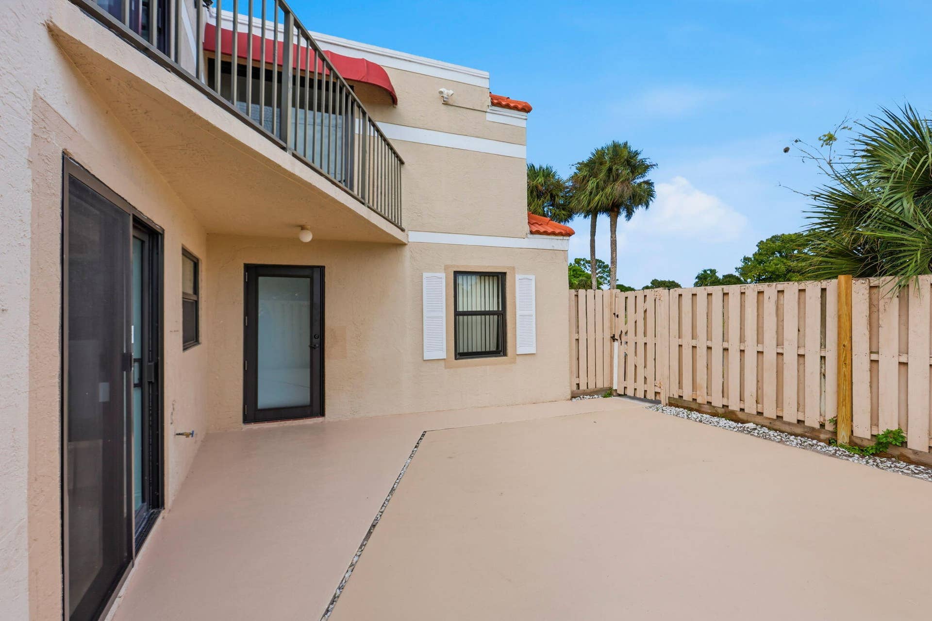 Private patio with a privacy fence, sliding glass door, and exterior entry door