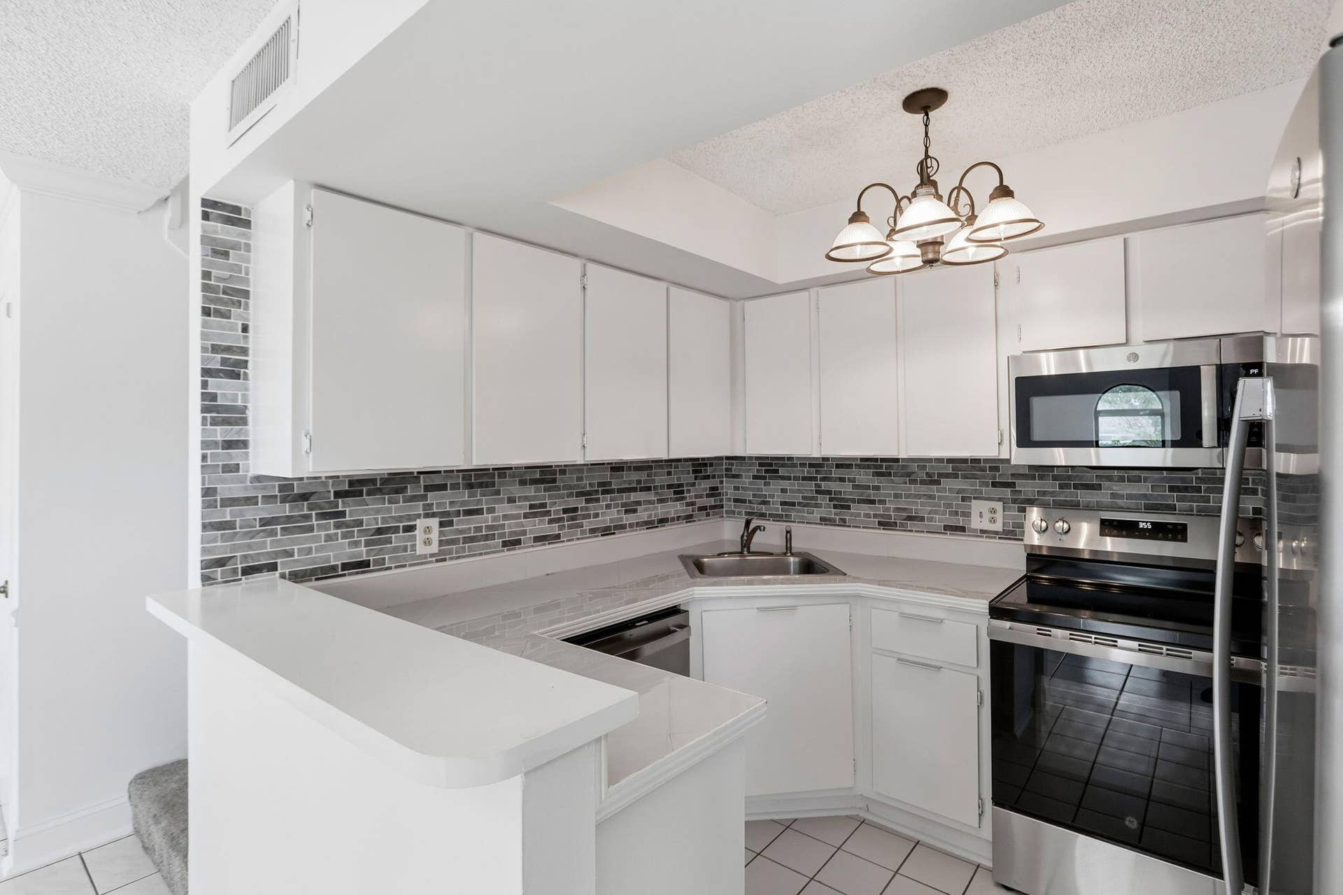 White cabinetry with full overlay doors, mosaic tile backsplash, NEW stainless steel appliances, and a breakfast bar