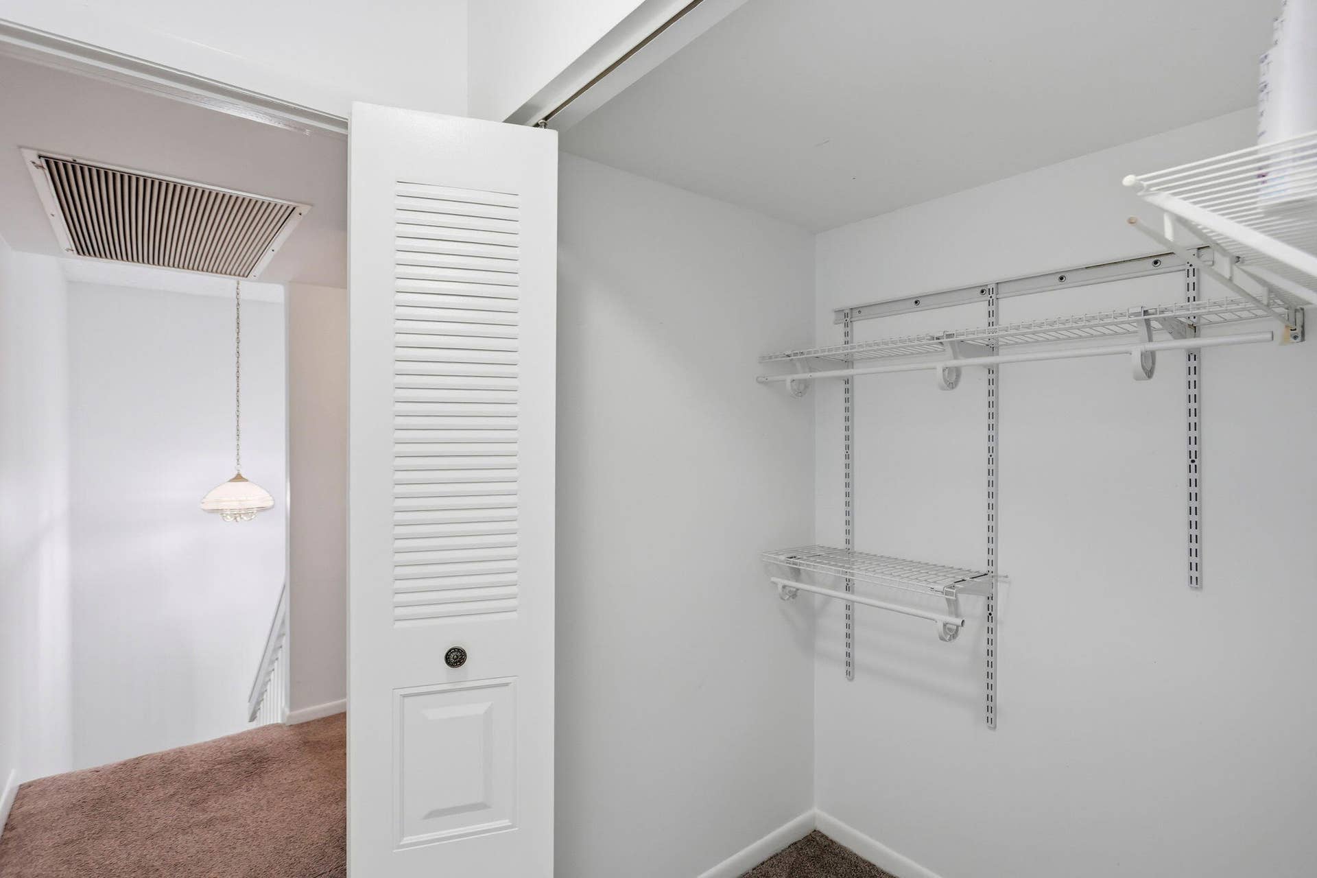 Walk-in closet with white wire shelving system and hanging rods