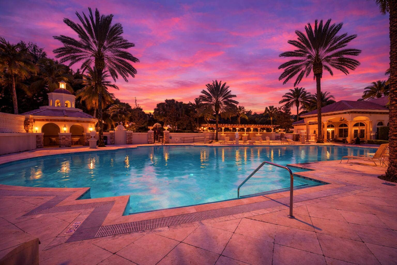 In-ground swimming pool featuring a stone-tile deck, poolside pergola, covered pavilion, and mature palm trees
