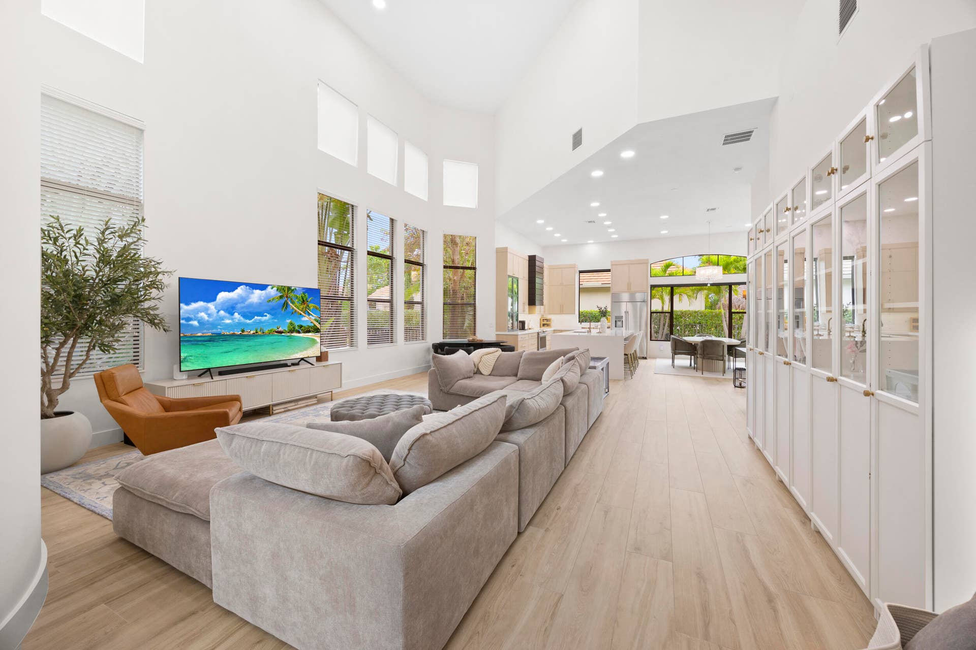 Vaulted ceilings, expansive windows, light-toned wood-finish flooring, and built-in floor-to-ceiling glass-paneled cabinetry