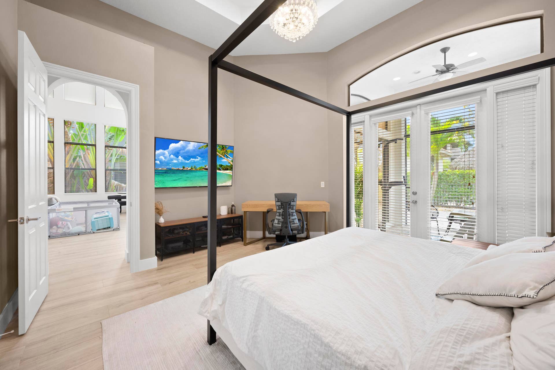 High ceilings with tray detailing, crystal chandelier, arched entryway, wood-finish flooring, and glass French doors