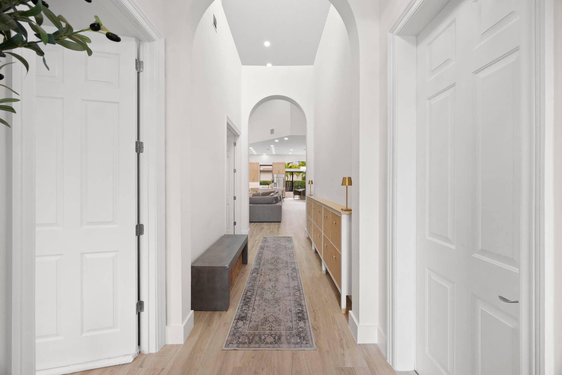 Hallway featuring architectural arched entryways, high ceilings, wood-finish flooring, and recessed lighting