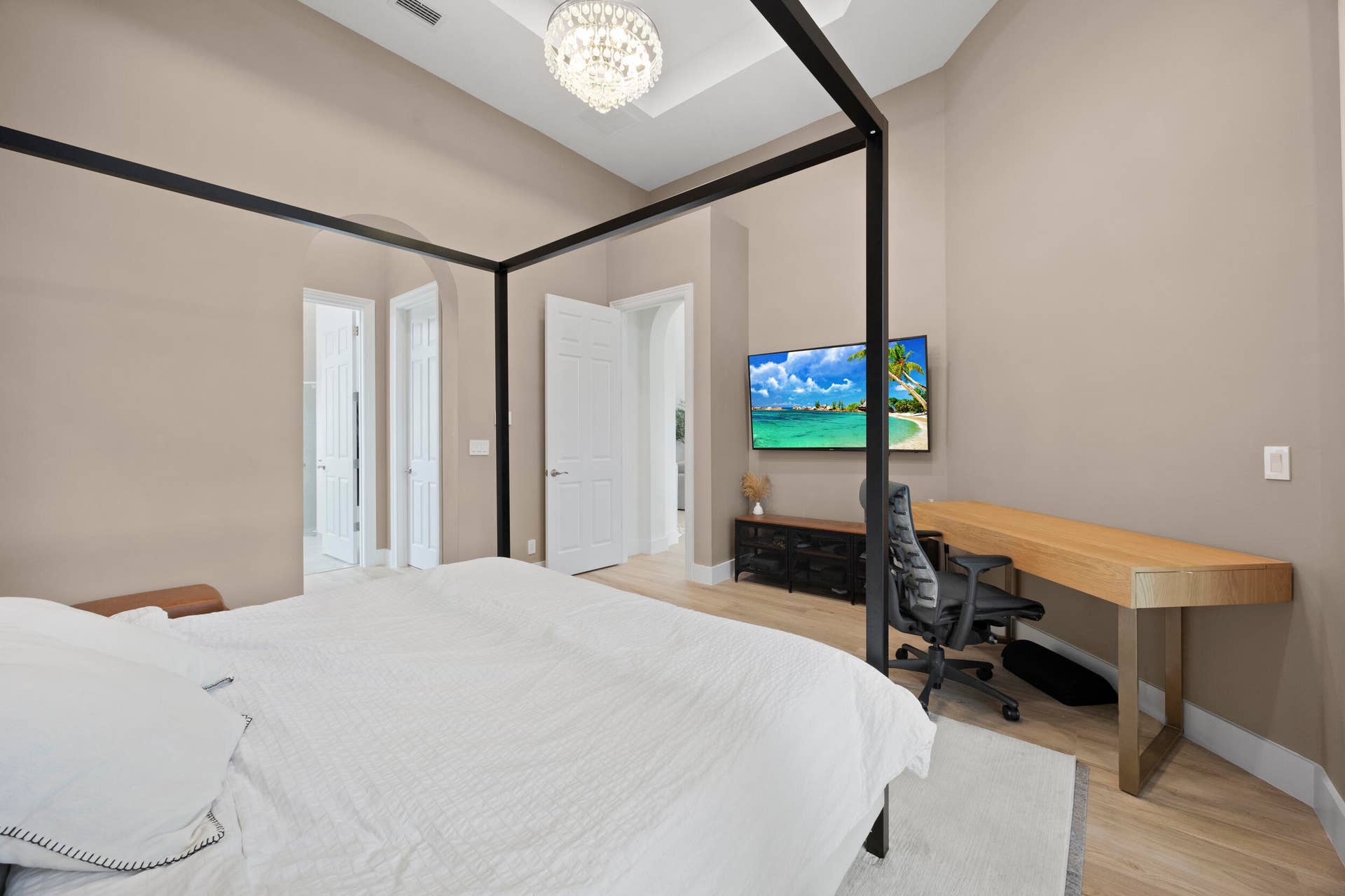 Room featuring high ceilings with a tray ceiling detail, recessed lighting, a decorative chandelier, archway architectural elements, and light-toned wood-finish flooring