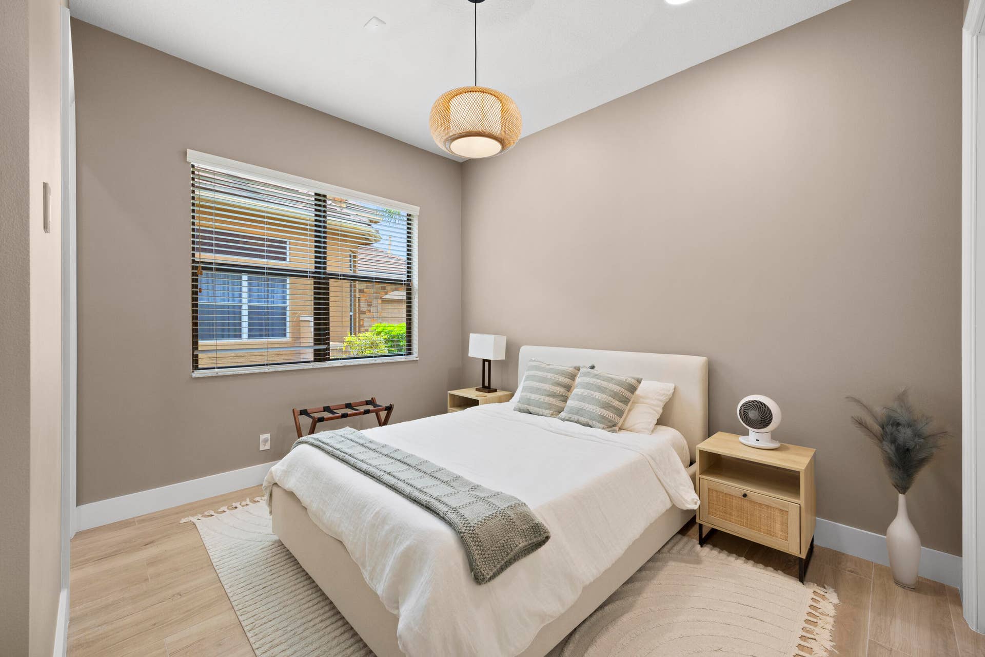 Neutral-toned interior featuring wood-finish flooring, a pendant light fixture with a textured woven shade, and a horizontal sliding window with integrated blinds