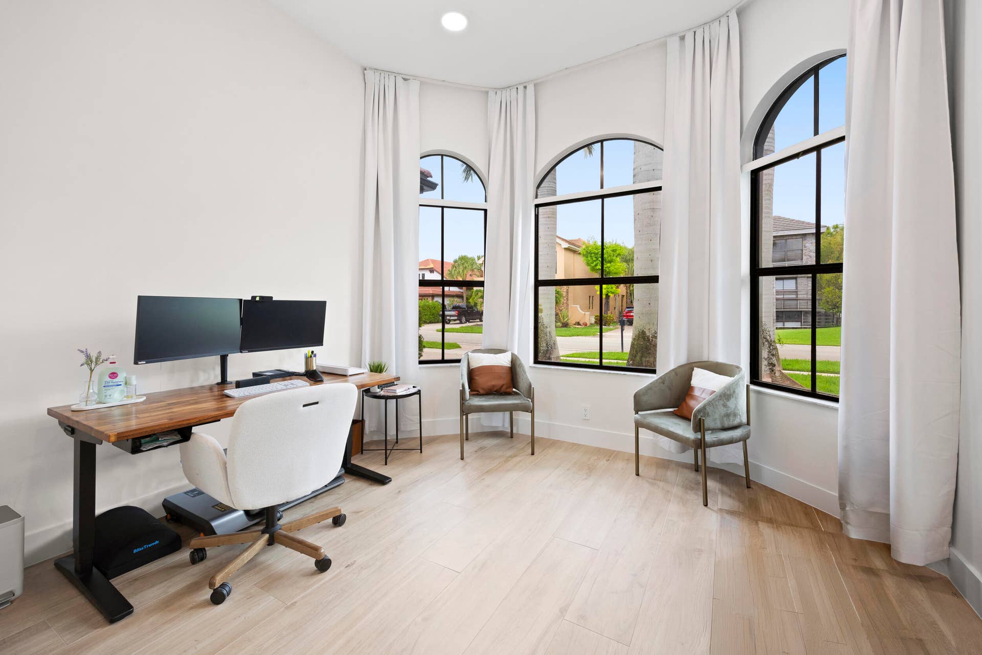 Room featuring wood-finish flooring, three arched windows with black frames, and recessed lighting