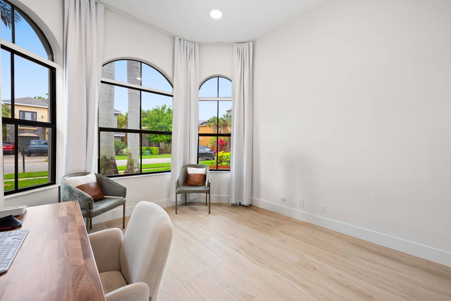 Arched windows with black frames, wood-finish flooring, and recessed ceiling lighting