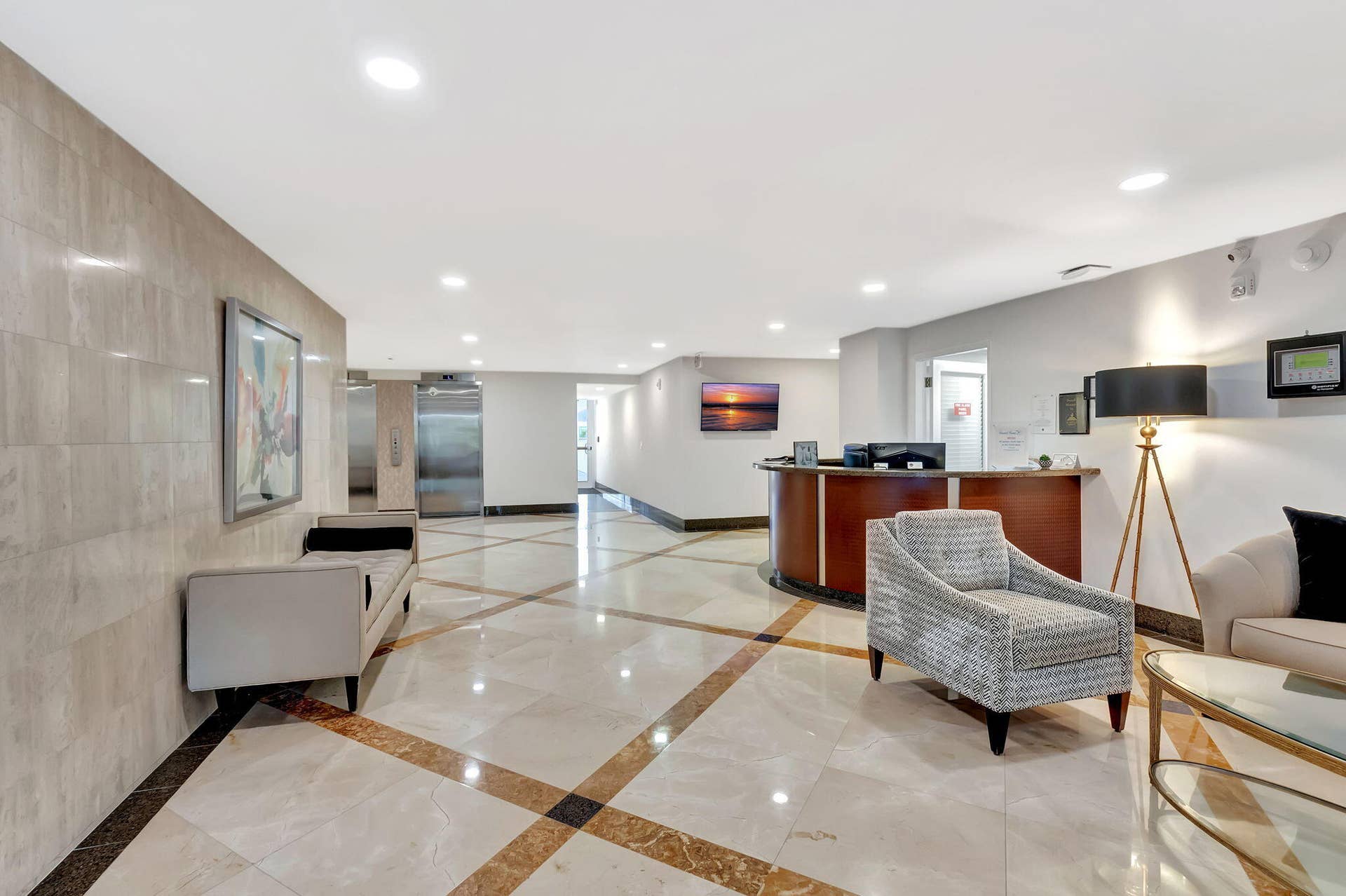 Lobby featuring polished stone flooring with inlaid detailing, stone-tiled accent wall, curved built-in reception desk, and recessed ceiling lighting