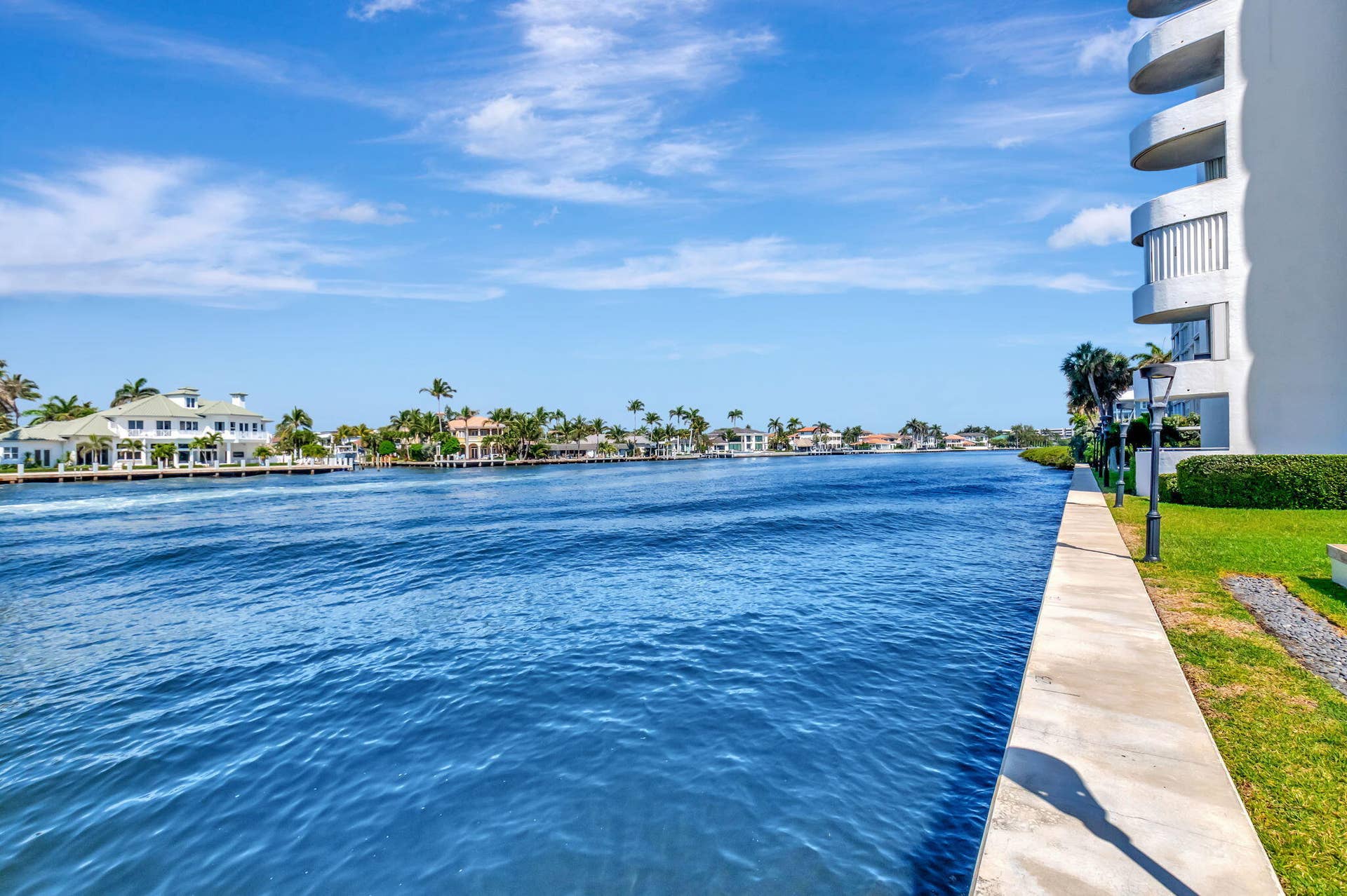Concrete seawall, manicured lawn, and exterior building balconies featuring structural railing systems