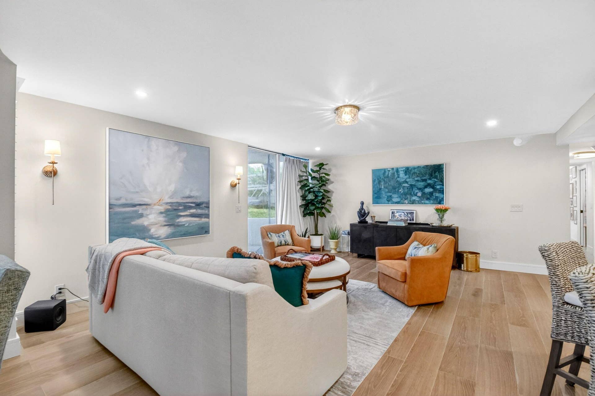 Open-concept living space featuring wood-finish flooring, recessed lighting, dual wall-mounted sconces, and glass patio doors