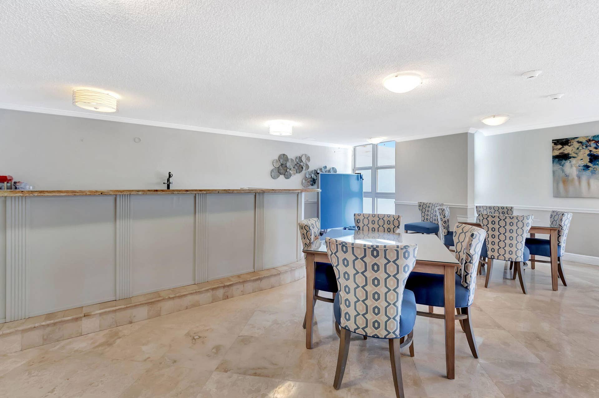 Built-in bar featuring a raised stone countertop, neutral cabinetry, and polished stone flooring throughout