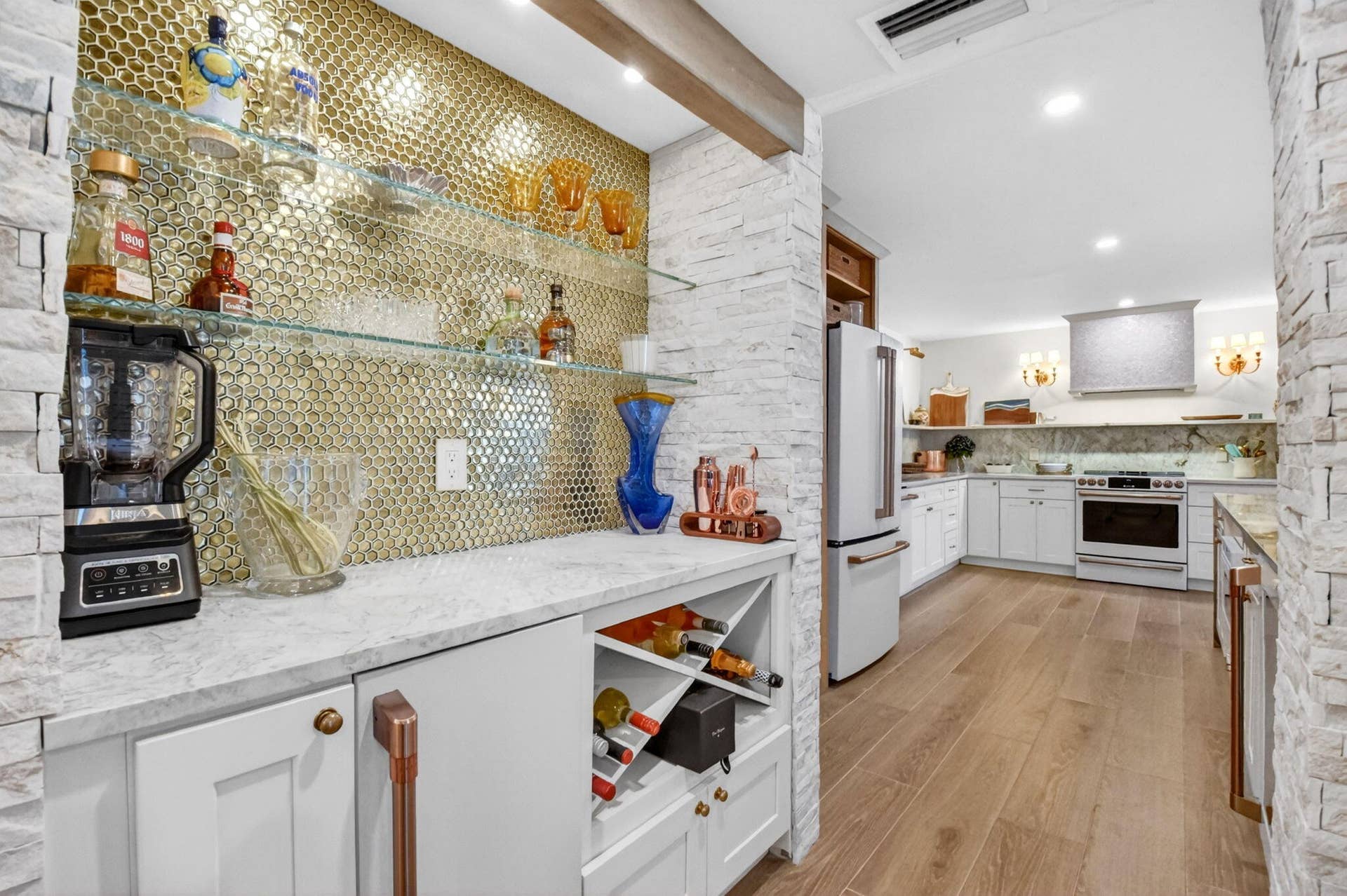 Custom wet bar featuring a stone-clad backsplash, built-in wine storage, floating glass shelving, stone countertop, and custom cabinetry