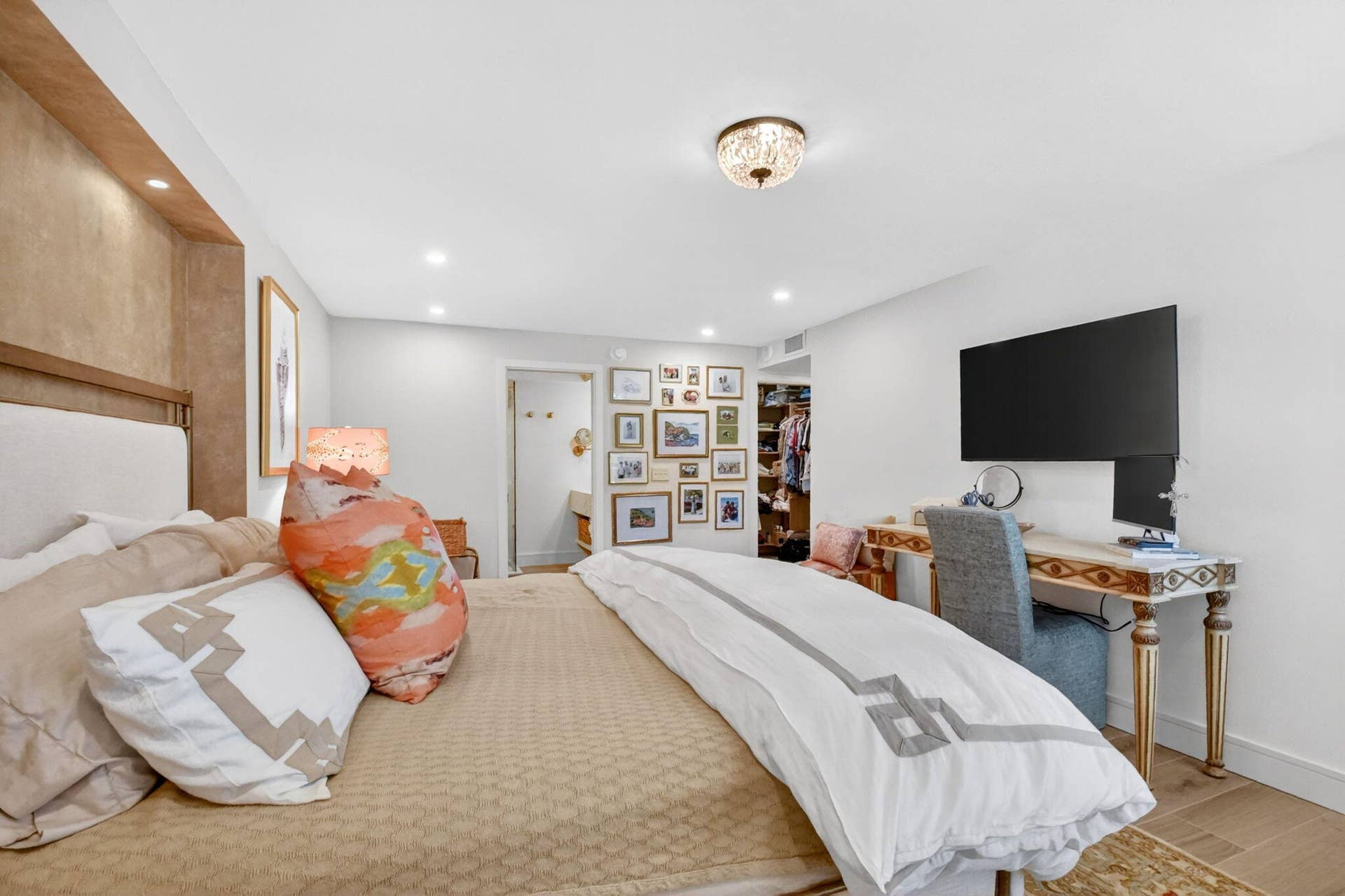 Recessed ceiling lighting, decorative flush-mount fixture, built-in recessed headboard alcove, and wood-finish flooring